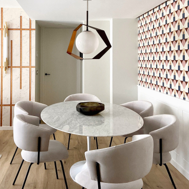 Modern dining area featuring a distinctive black and gold pendant light over a round marble table with plush cream chairs.