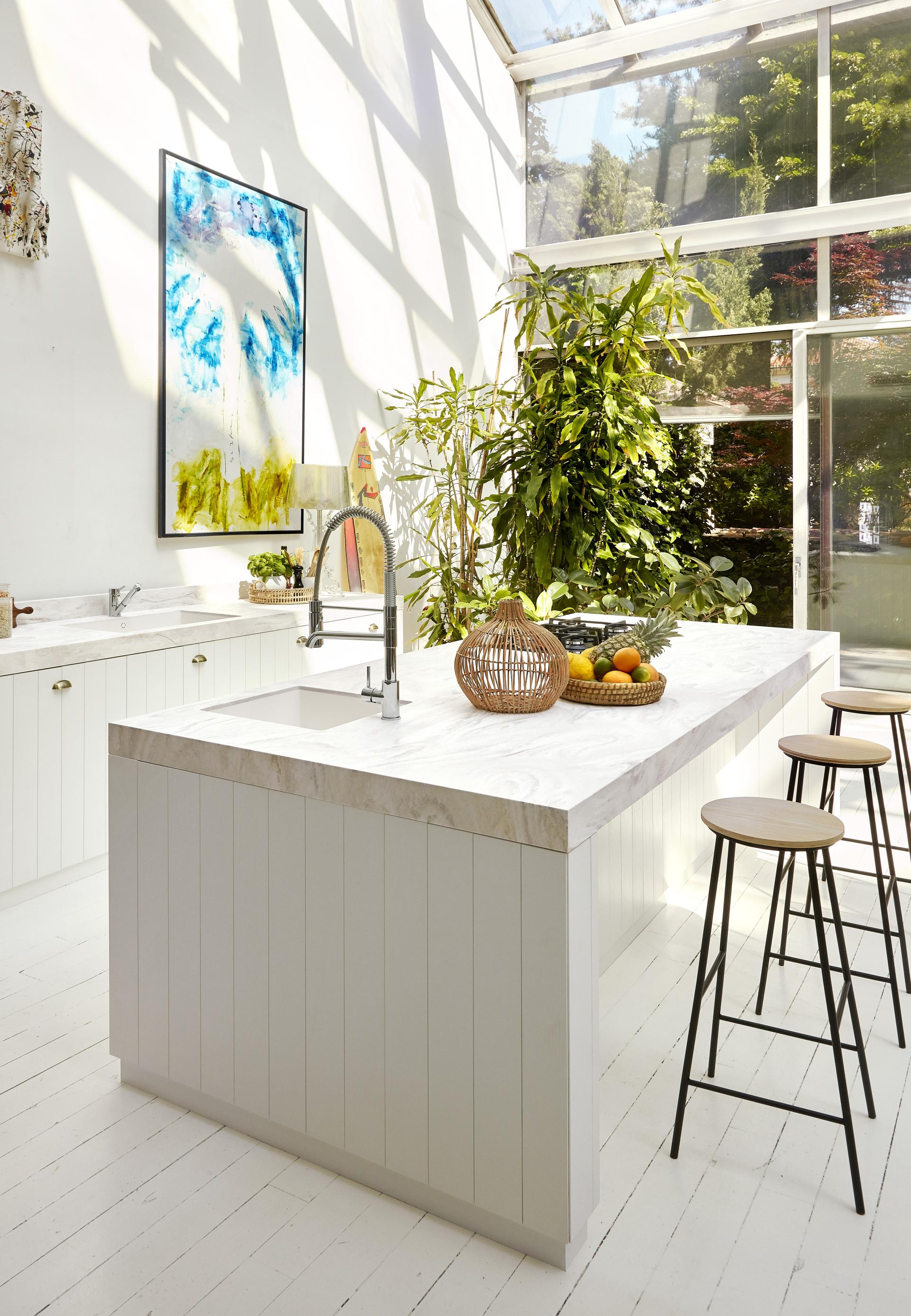 Modern kitchen featuring a Corian countertop, bright natural light, and vibrant greenery for a fresh, stylish atmosphere.