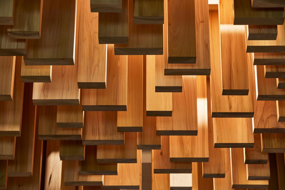 American Tulipwood Pavilion artwork by David Adjaye, showcasing suspended wooden panels in a dynamic arrangement.