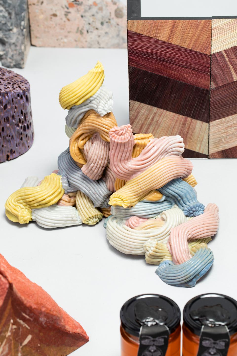 Colorful sculptural materials, including soft textures and patterns, represent innovative approaches to sustainability in design.