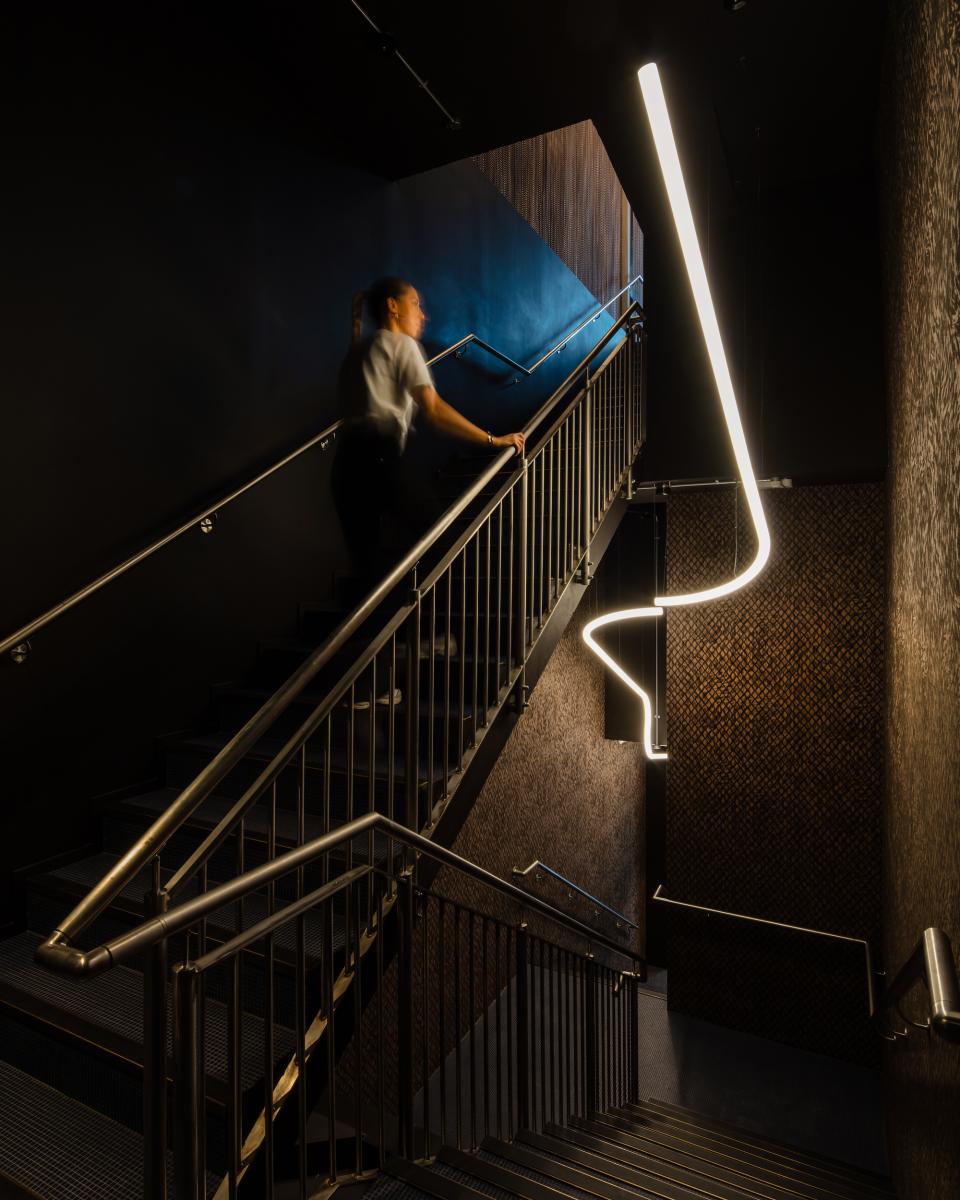 Modern staircase leading to M'Arks Sky Bar, featuring sleek design and ambient lighting in London.