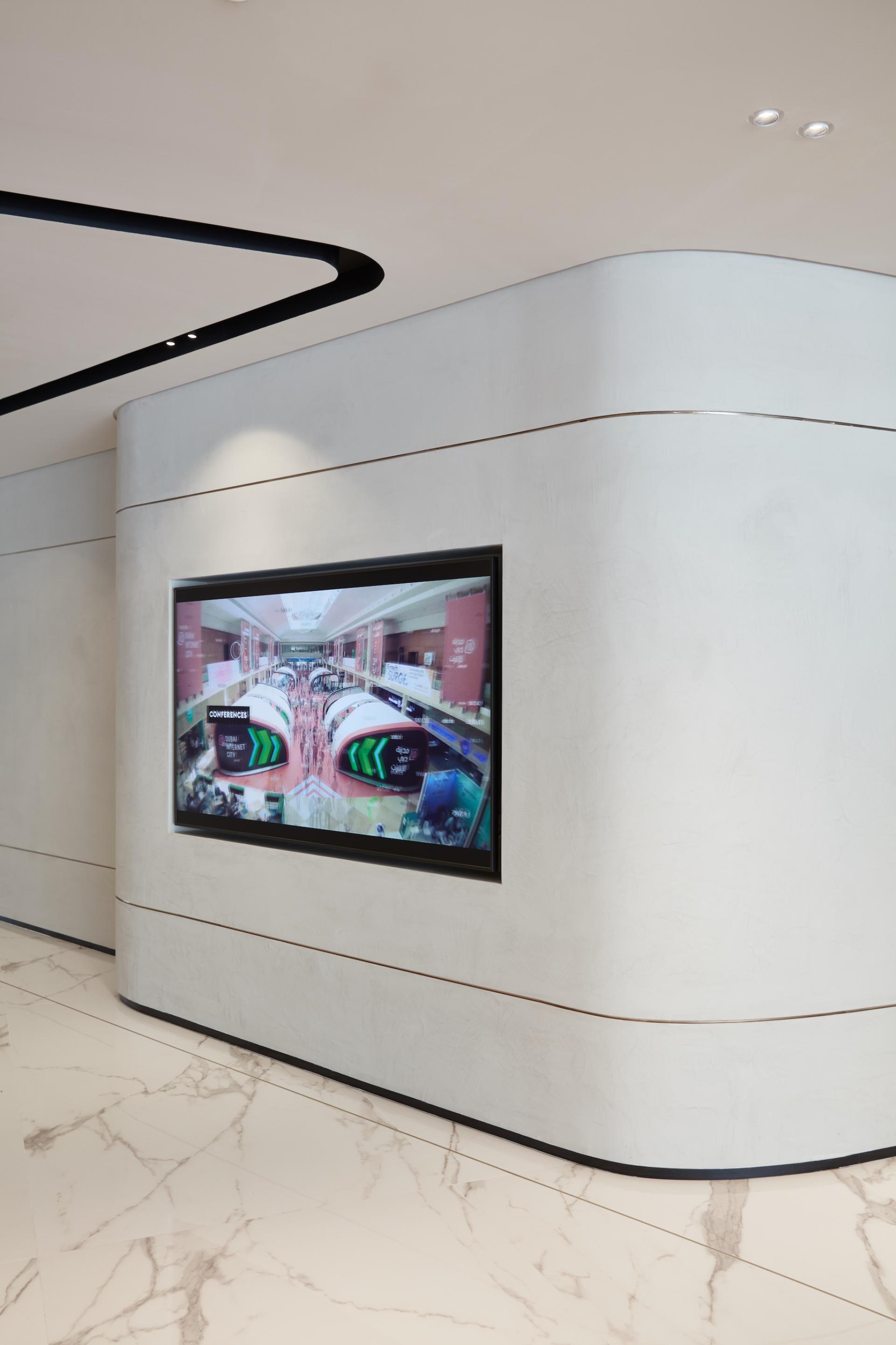 Modern interior of Dubai Internet City management offices featuring a large digital display on a textured wall.