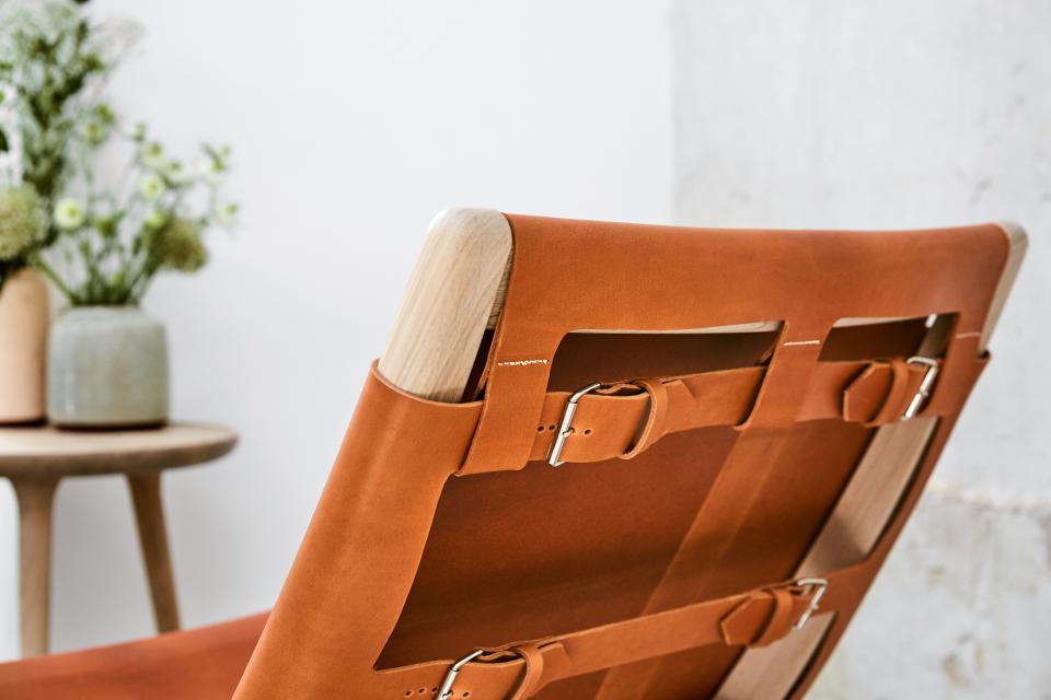 Elegant rocking chair by Mater, designed by Shawn Place, featuring a soft leather backrest and wood frame.