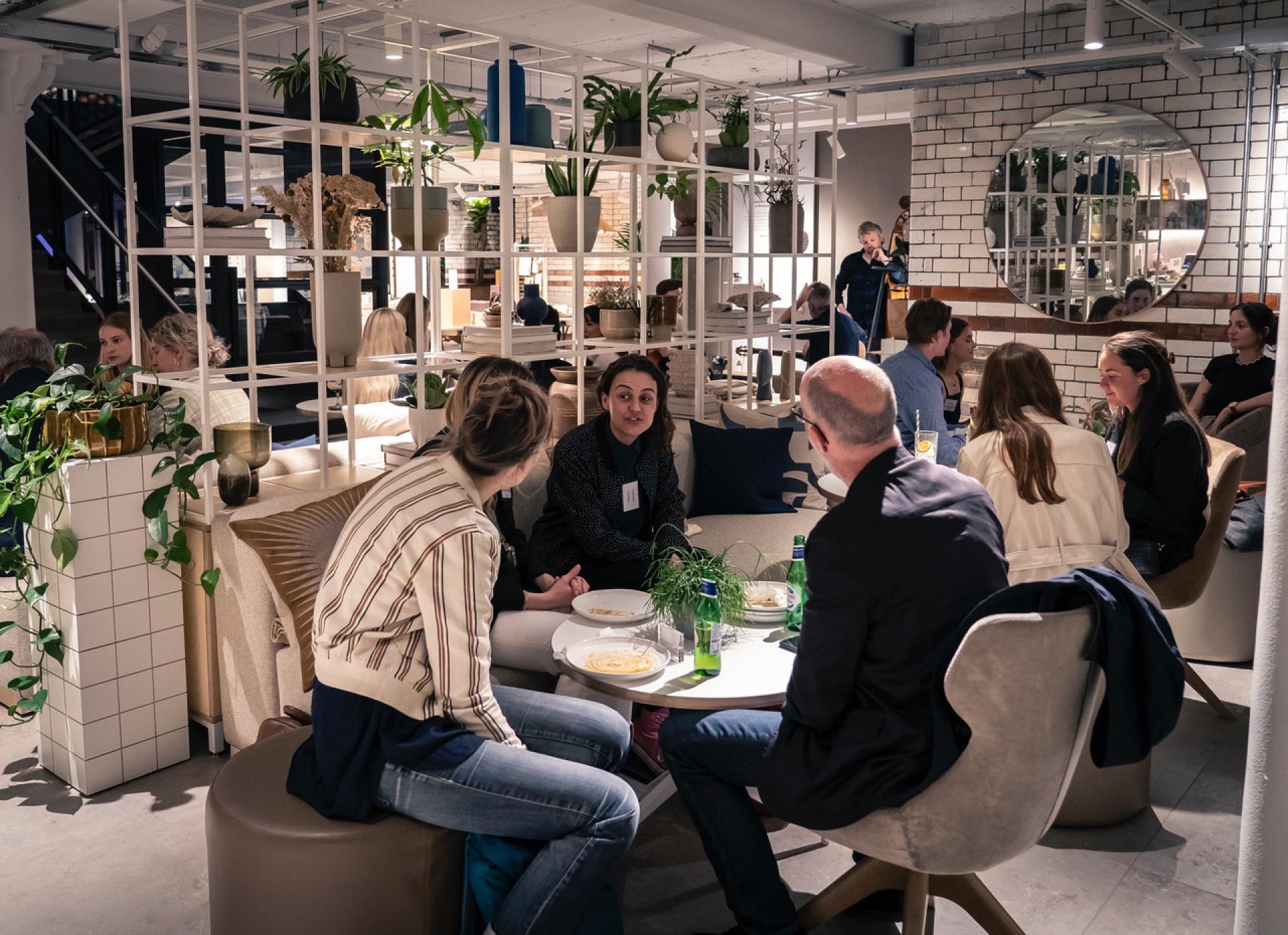 Guests engaged in conversation at a stylish venue, celebrating the conclusion of the From The Ground Up exhibition on biomimicry.