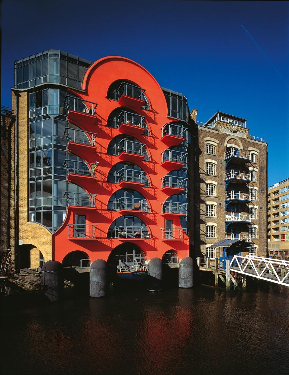 Contemporary red architectural building contrasting with historical warehouse, highlighting postmodernism in British architecture at Sir John Soane's Museum.