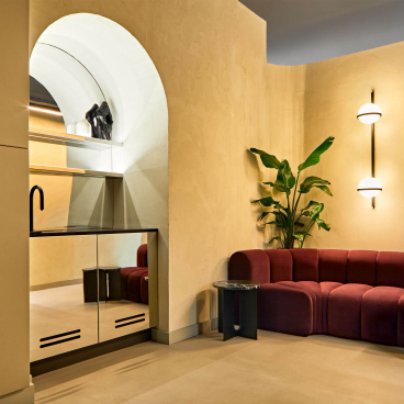 Modern reception area of Medika Clinic featuring plush red seating, sleek decor, and greenery for a comforting ambiance.