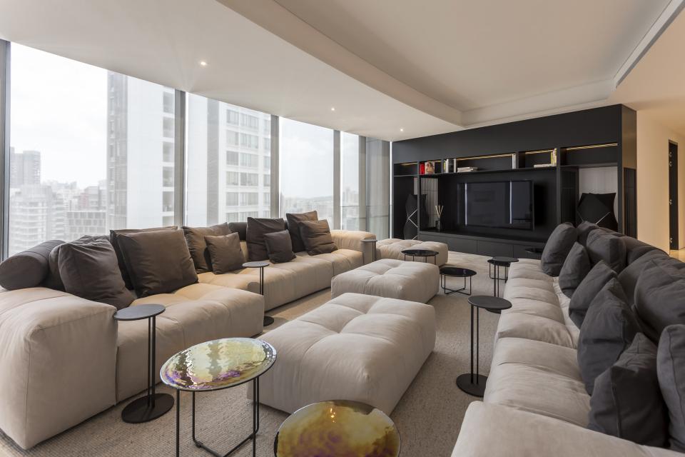 Stylish living room design featuring plush seating, modern decor, and large windows with city views, by Elliot James.