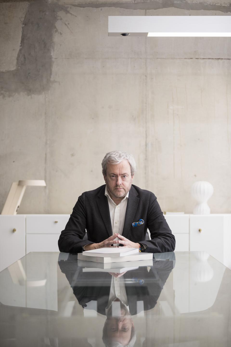 Mark Simpson, principal and head of design at BDP, seated at a modern glass table in an industrial workspace.