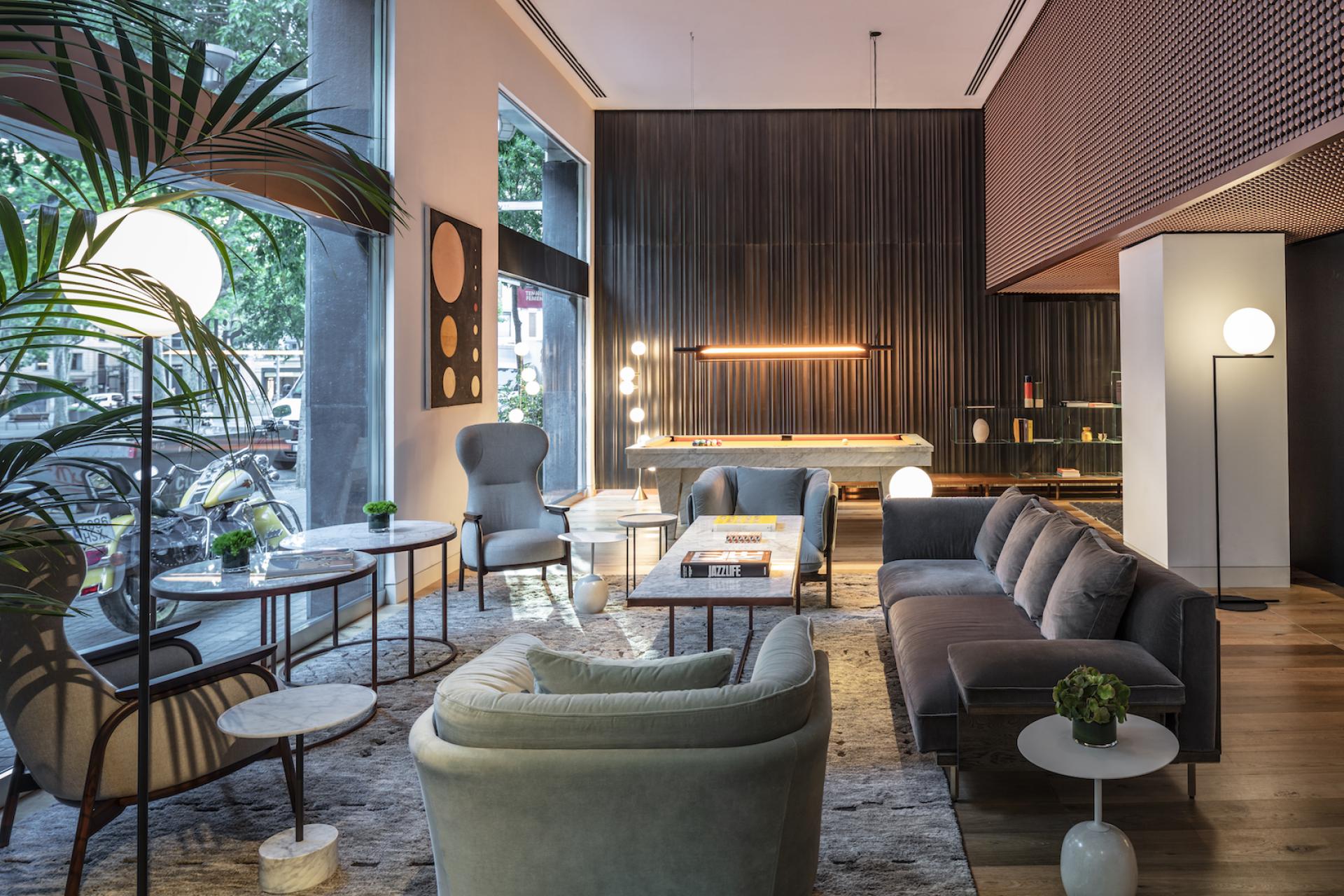 Stylish lounge area of Sir Victor hotel in Barcelona, featuring modern furniture, decorative plants, and natural light.