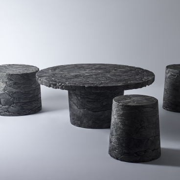 Innovative black styrofoam furniture set, including a round table and four stools, highlighting eco-friendly design in Tokyo.