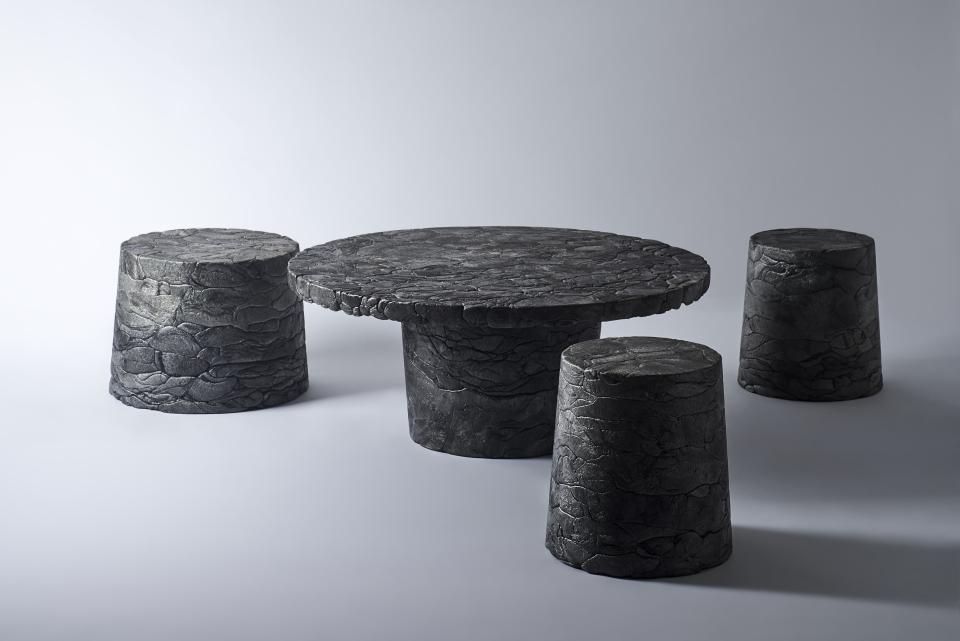 Innovative black styrofoam furniture set, including a round table and four stools, highlighting eco-friendly design in Tokyo.