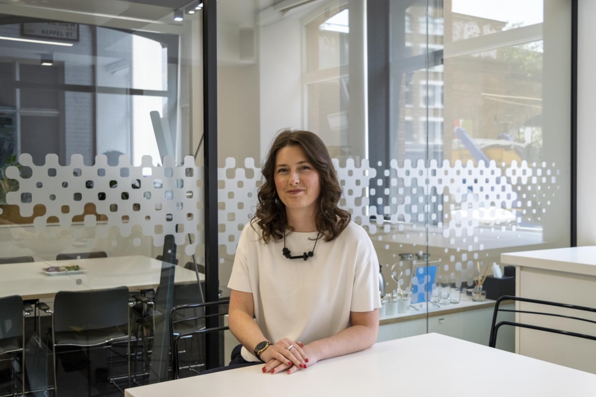Professional woman seated at a modern office table, reflecting on inspiration from 2021's top interviews and discussions.