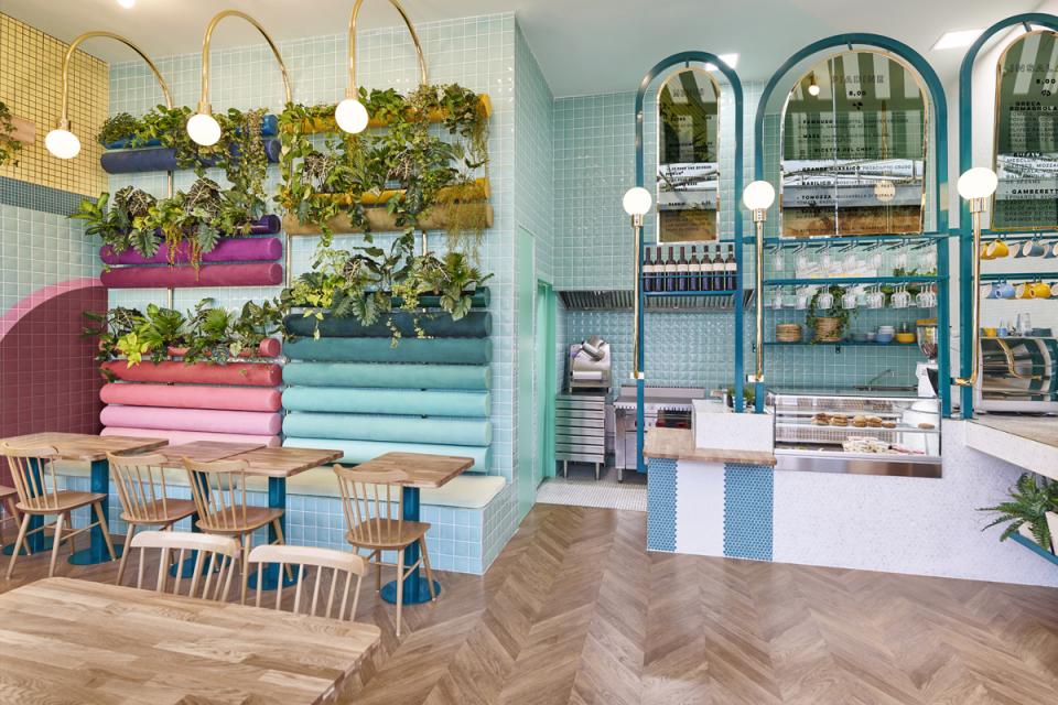 Lively interior of Piada restaurant in Lyon, featuring colorful seating, greenery, and a modern open kitchen design.