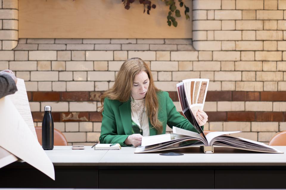 A woman in a green blazer reviews design materials at Material Source Studio in Manchester.