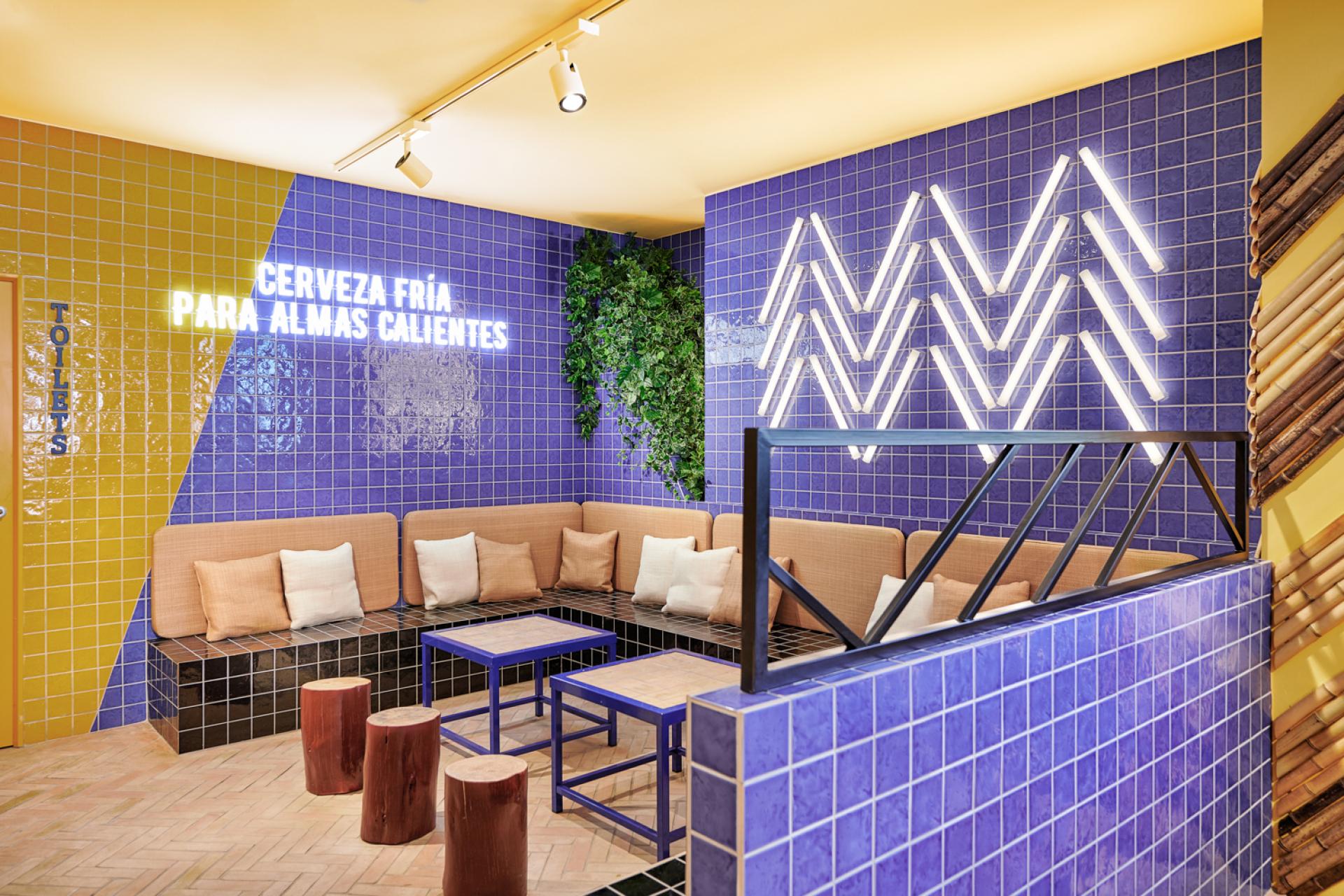 Brightly colored interior of Bar TORÖ in Ibiza, featuring Mediterranean-inspired tiles, seating, and neon signage.