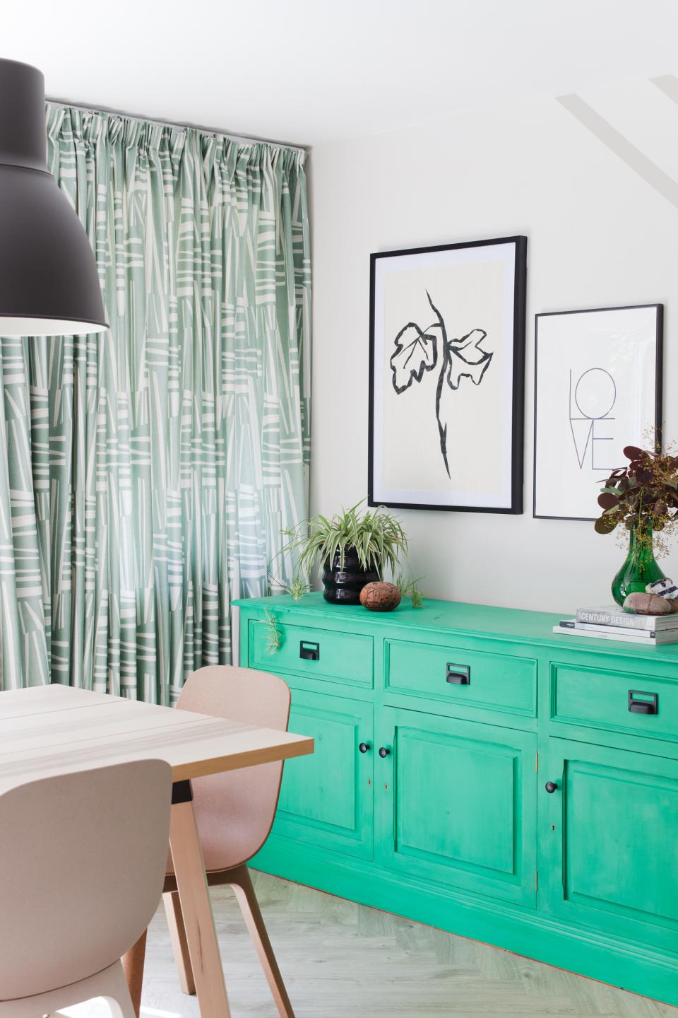 Scandi Industrial dining area featuring a vibrant green sideboard, patterned curtains, and minimalist decor elements.