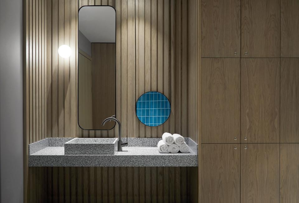 Modern bathroom interior design featuring a stylish sink, round mirror, wood paneling, and decorative blue tiles.