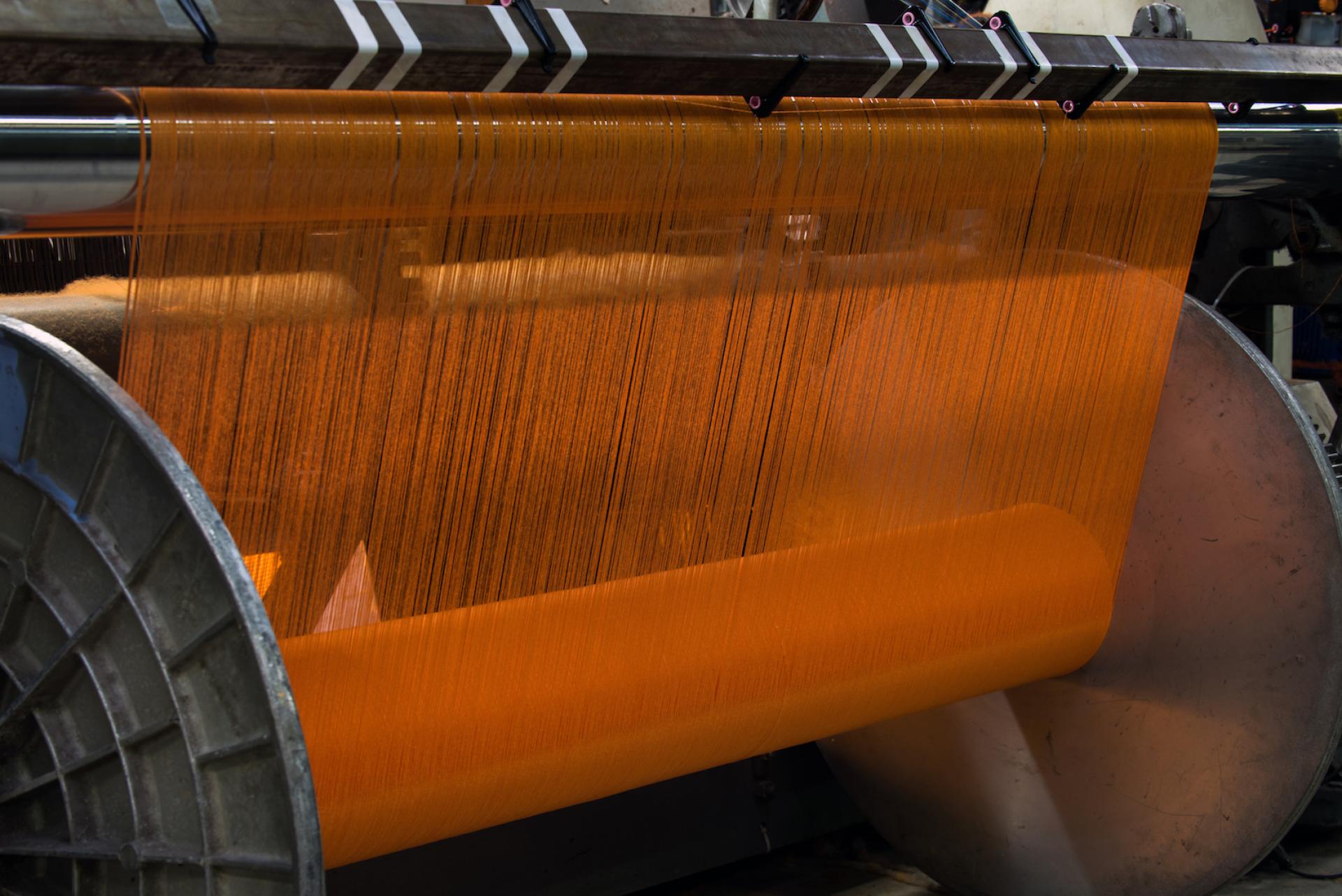 Textile manufacturing process showcasing vibrant orange threads being processed in a modern mill.