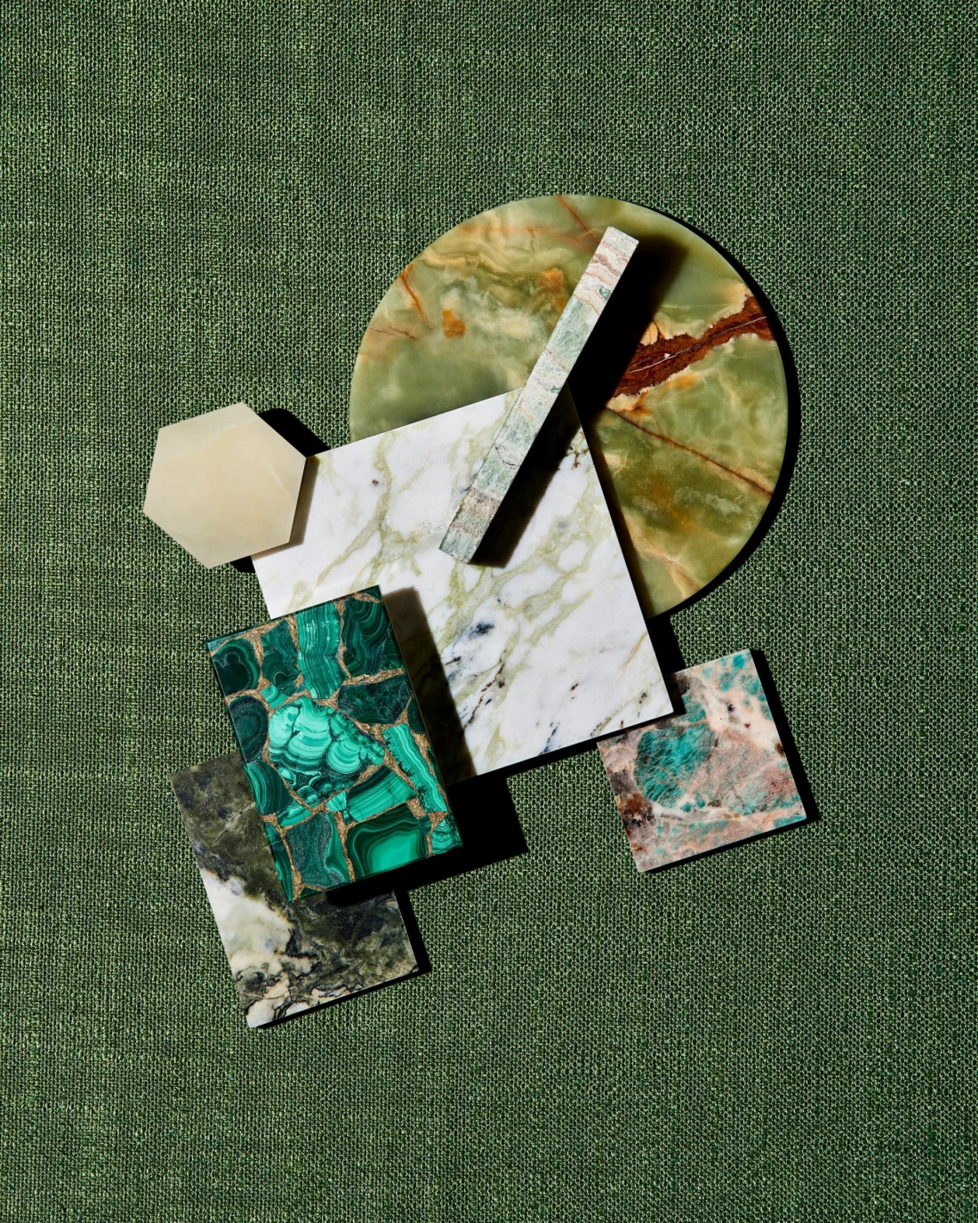 Colorful marble and stone samples arranged attractively on a green textured background, showcasing design trends from 2019.