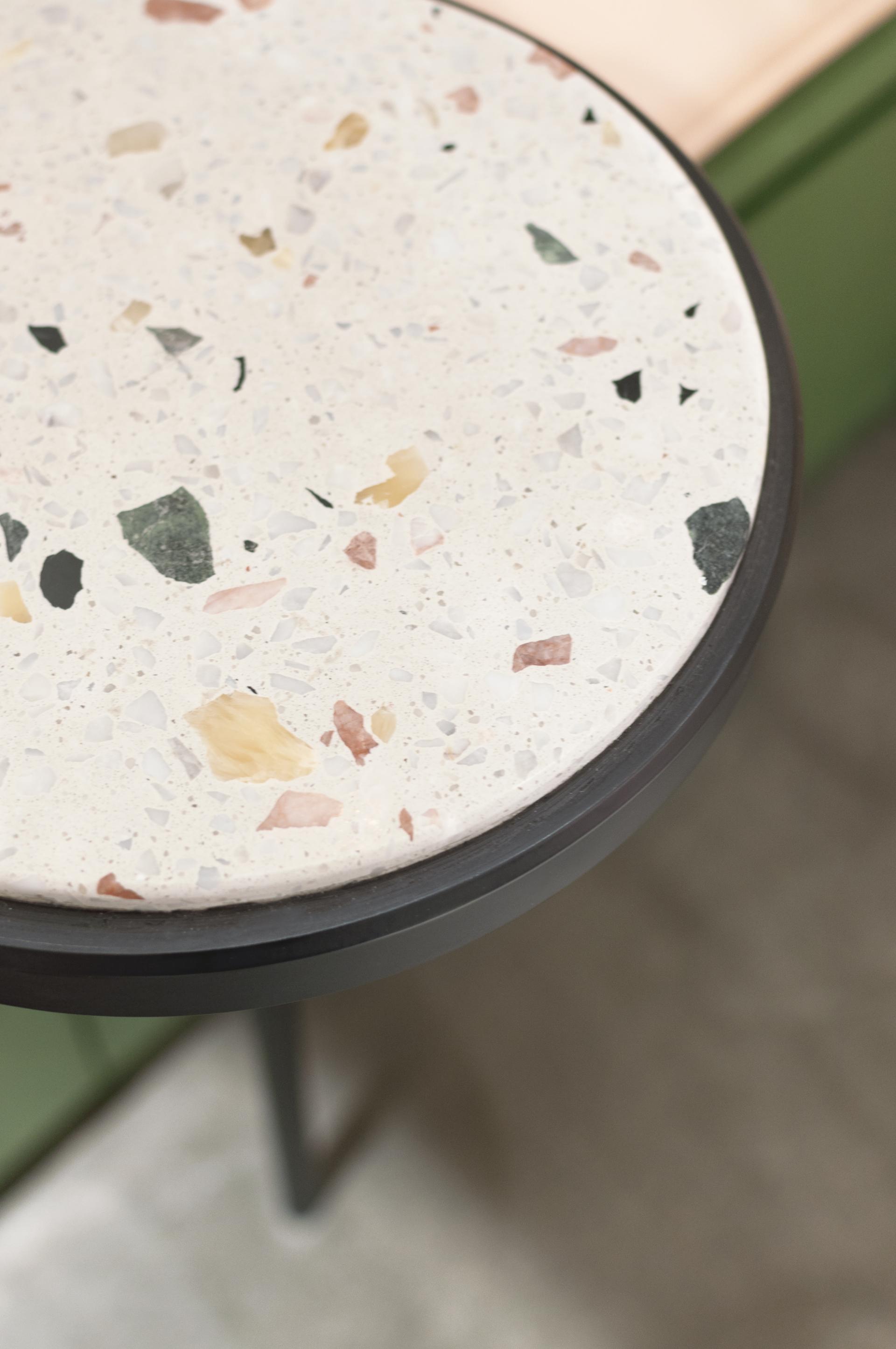 Close-up of a round terrazzo table displaying soft curves and unique colorful fragments, highlighting organic design elements.
