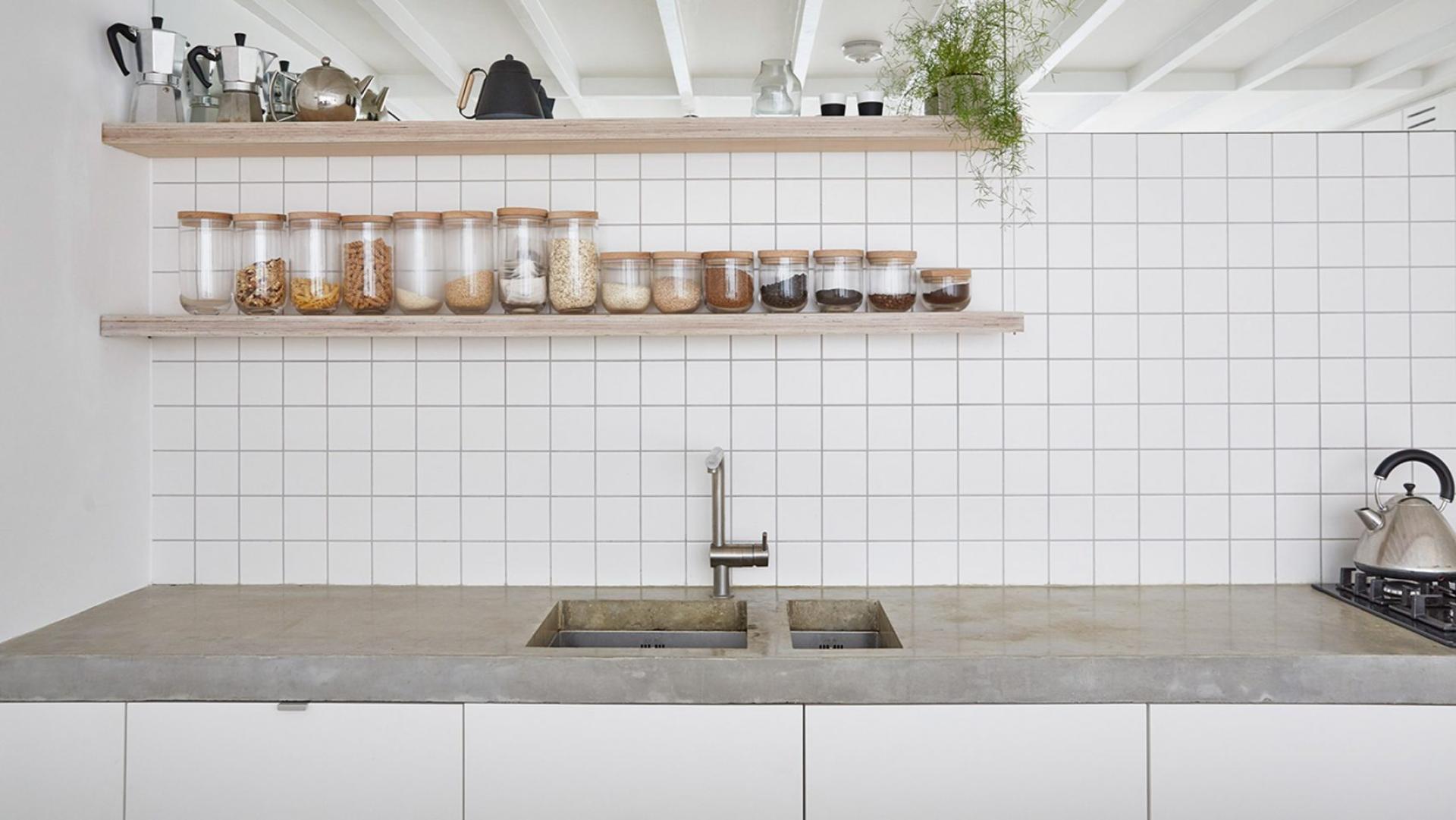 Modern kitchen with concrete countertops, glass jars of ingredients, and a minimalist design creates a serene atmosphere.