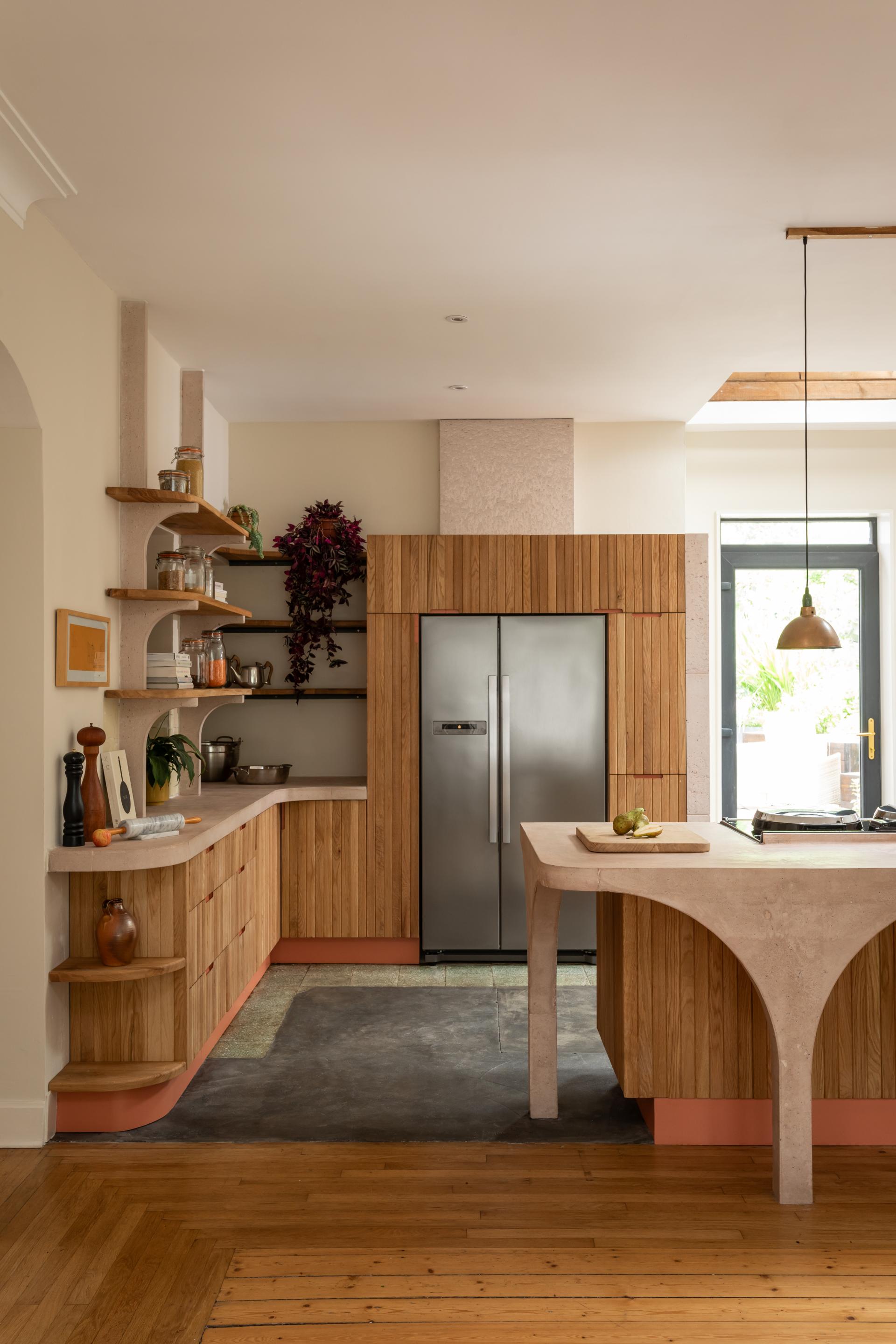 Modern kitchen design featuring poured pink concrete, Scottish Oak cabinetry, and an open layout with natural light.