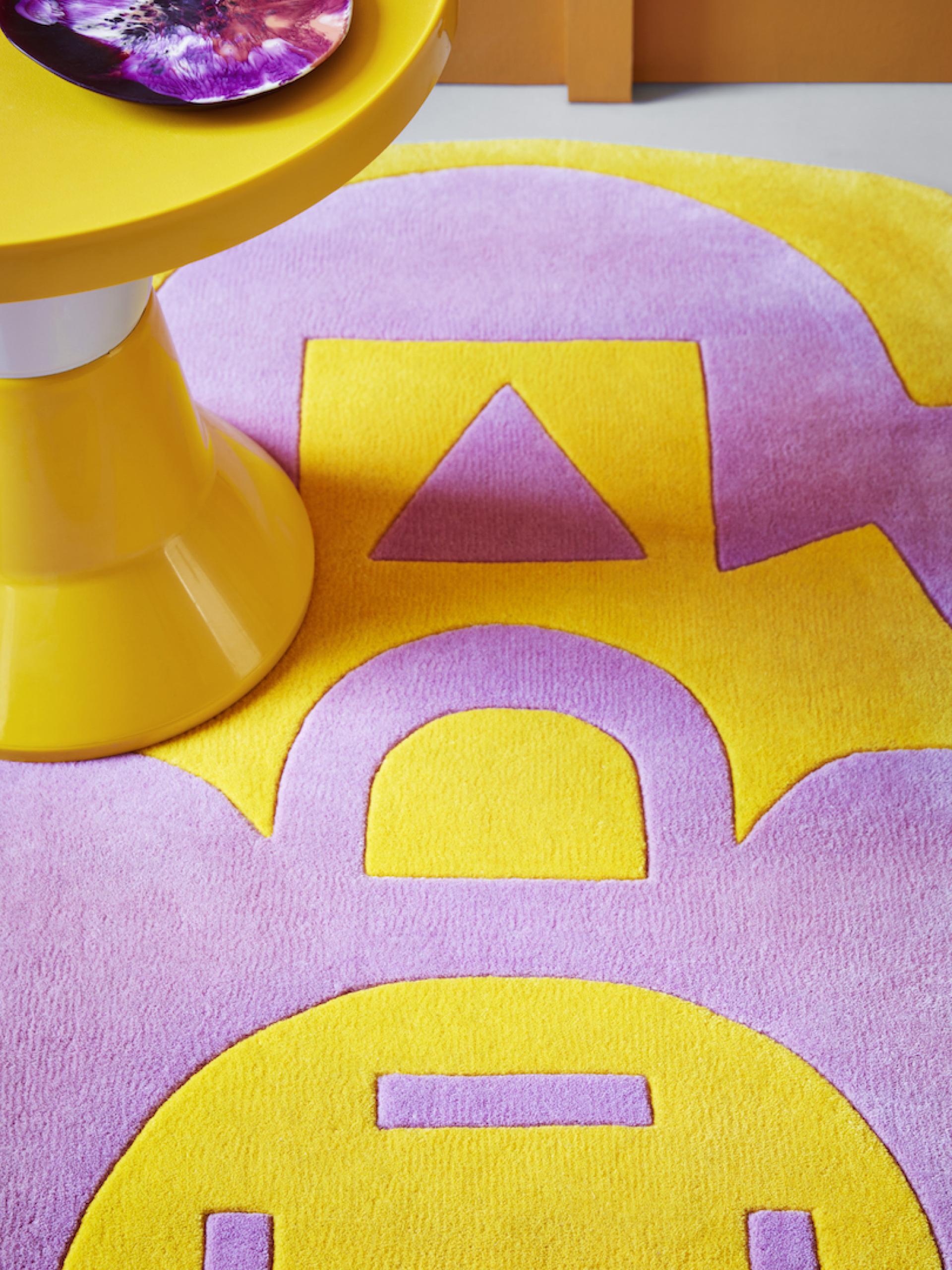 Vibrant Mediterranean-inspired rug in yellow and lavender, accentuated by a modern yellow side table and patterned plate.