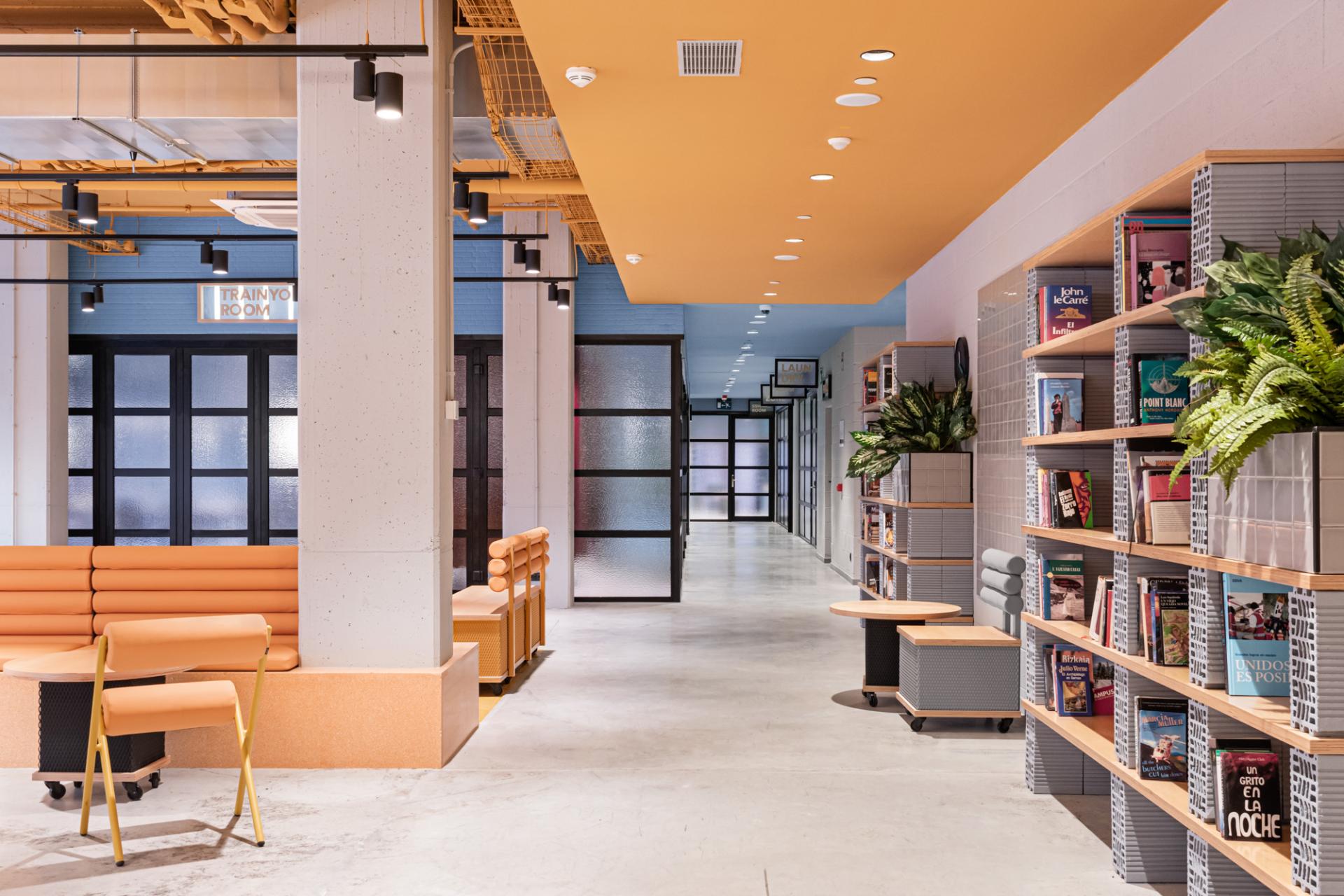 Brightly colored hallway in a Wes Anderson-style student residence, featuring modern furniture and bookshelves.