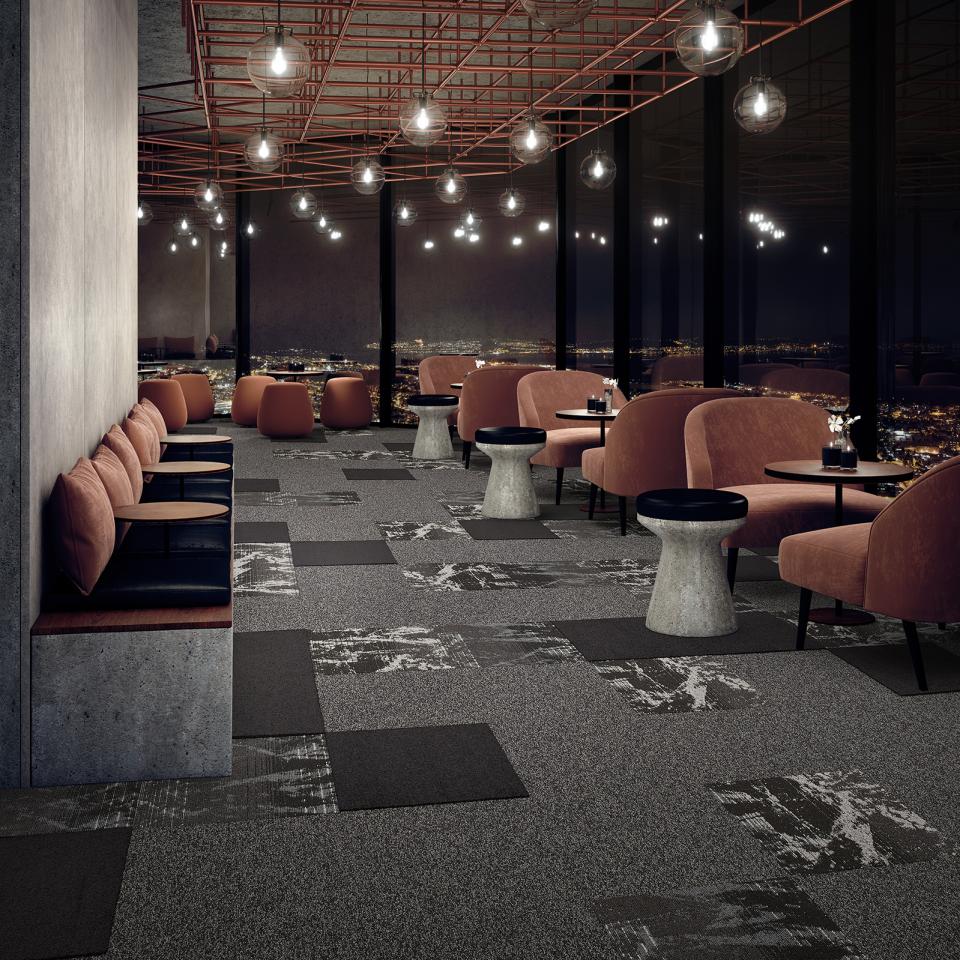 Stylish interior featuring modulyss Delight carpet tiles, with plush seating and a stunning cityscape view.