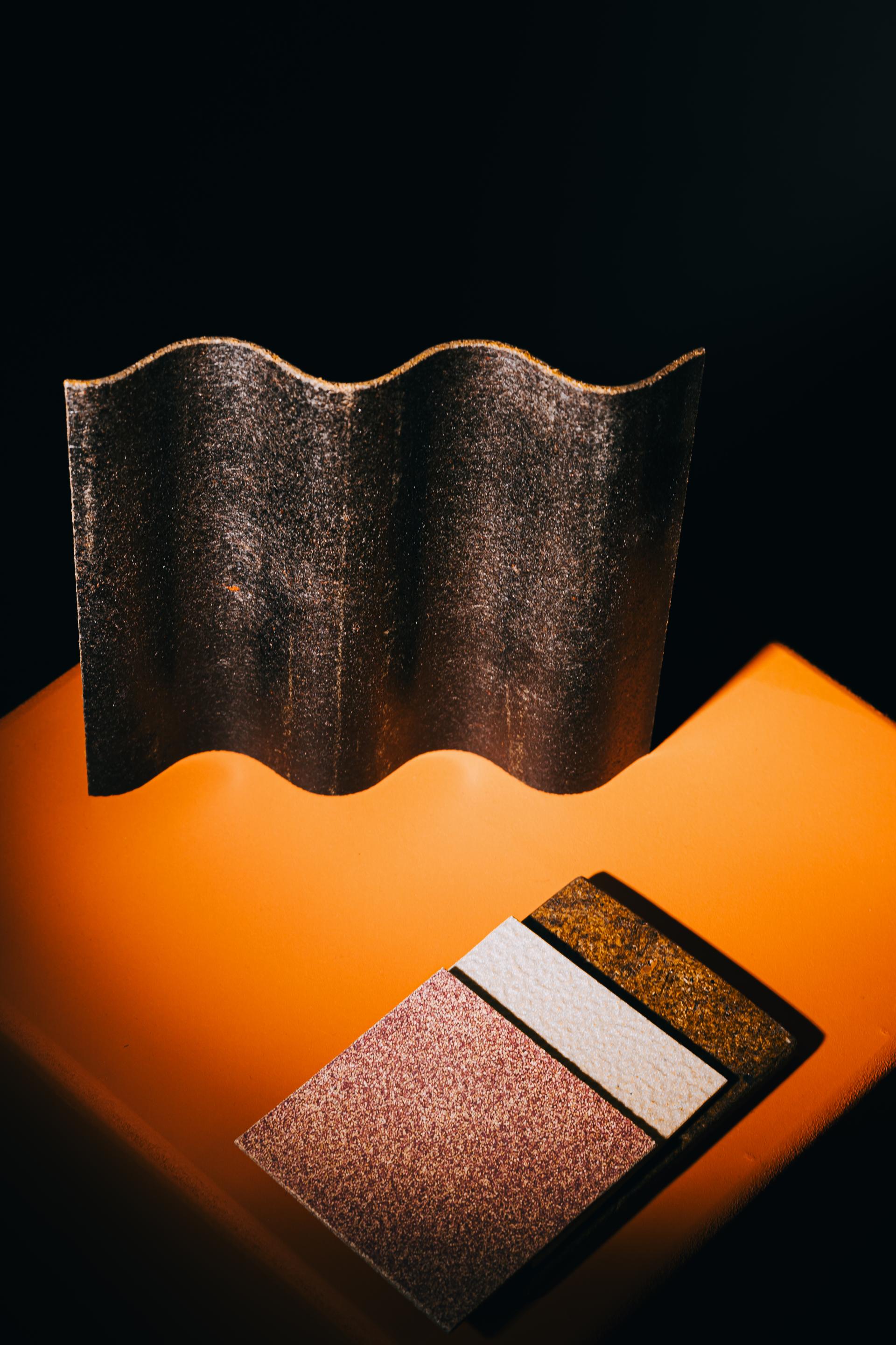 Innovative bio-materials displayed at the exhibition, showcasing textured panels and a wavy element on an orange surface.