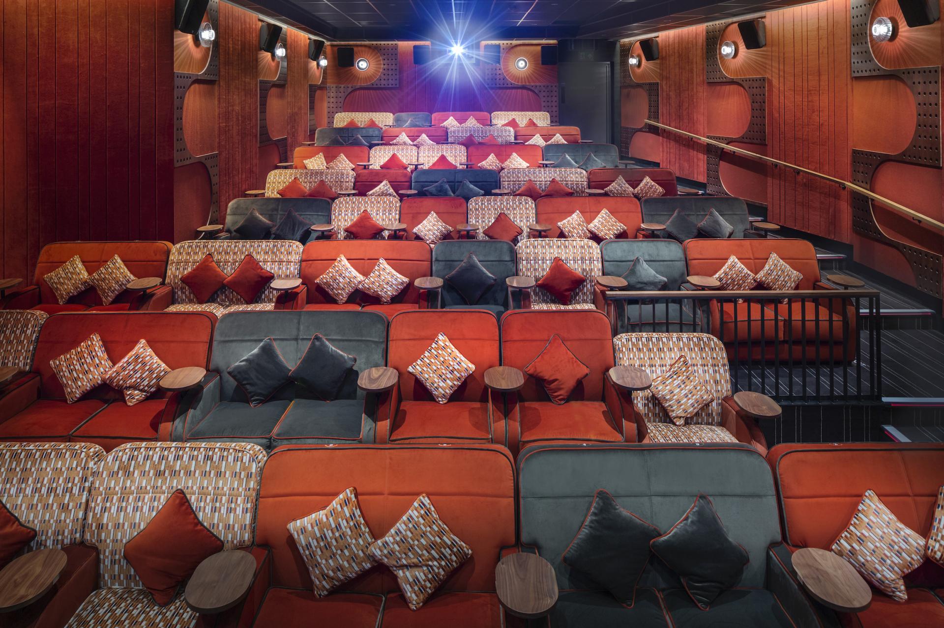 Stylish cinema seating with colorful cushions, showcasing design for comfort and acoustics in a noise-sensitive environment.