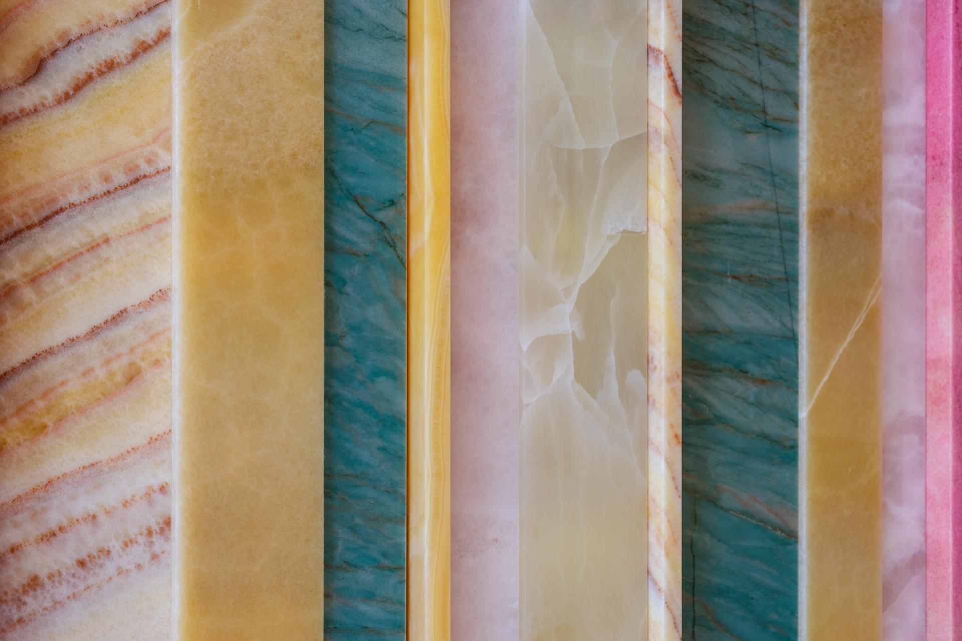 Colorful onyx slabs in various hues, showcasing the stunning natural stone used by SolidNature for the &C project.
