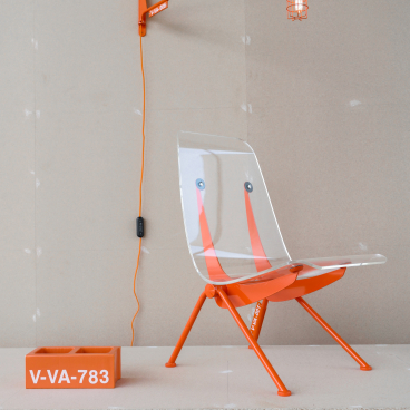 Vitra's futuristic chair designed by Virgil Abloh, featuring a transparent seat and vibrant orange accents, on display.