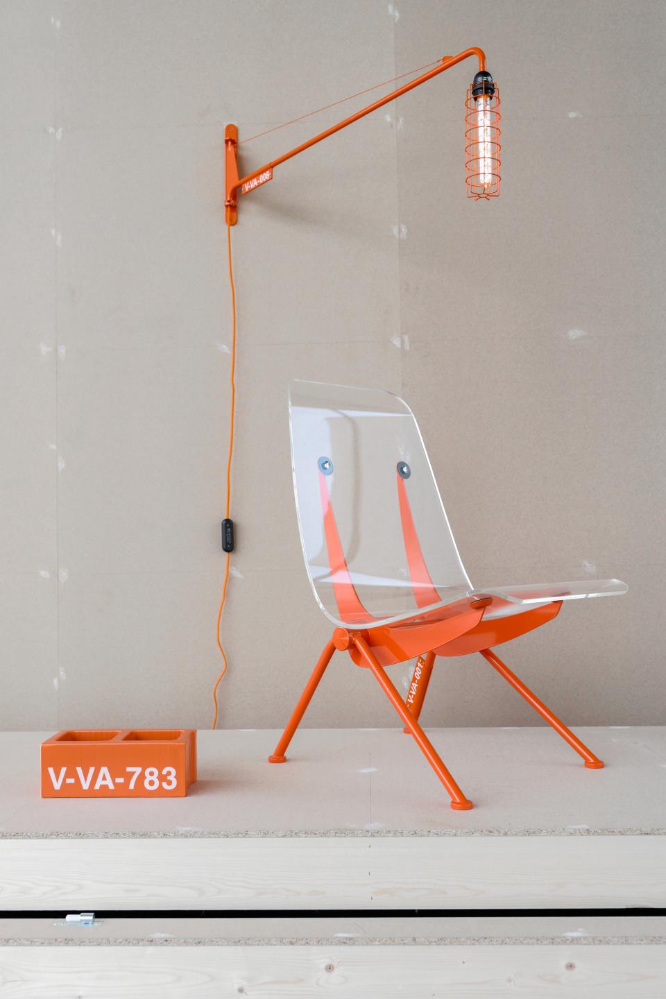 Vitra's futuristic chair designed by Virgil Abloh, featuring a transparent seat and vibrant orange accents, on display.
