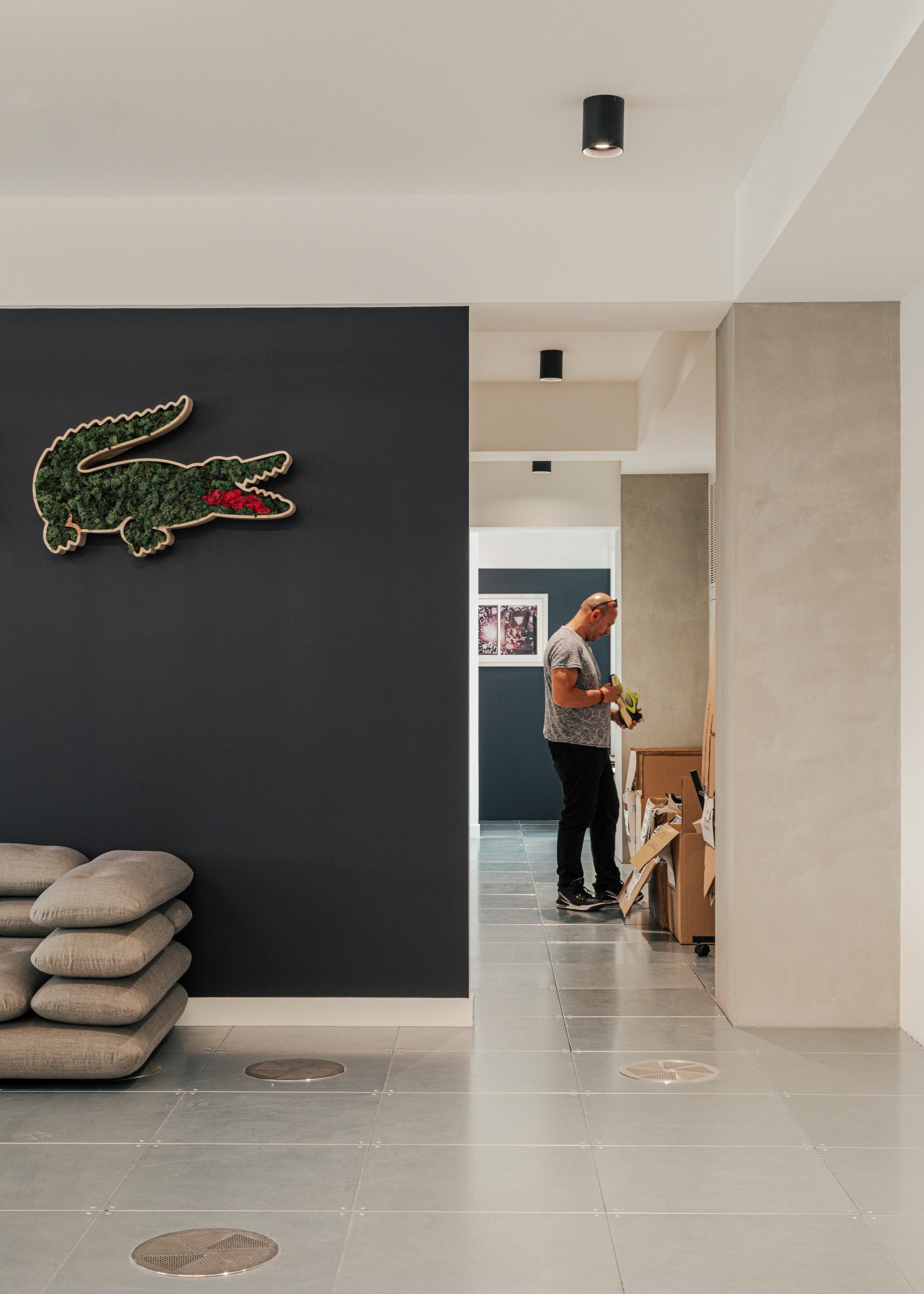 Lacoste-inspired workspace featuring a moss-covered crocodile logo and modern interior design elements in London.