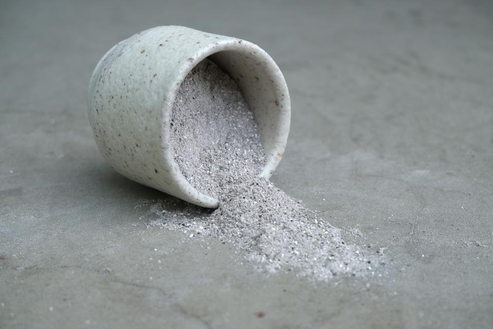 Ceramic container spilling innovative grey material, showcasing trends in surface design and material innovation at the Surface Design Show.