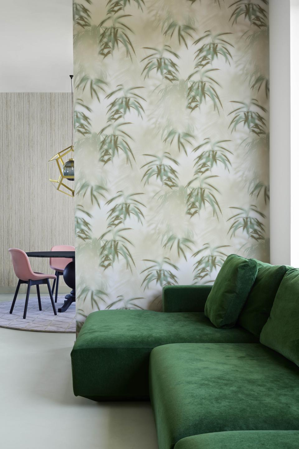 Elegant green sofa in a contemporary space featuring Tektura Wallcoverings' bamboo-patterned wallpaper from the Material World collection.