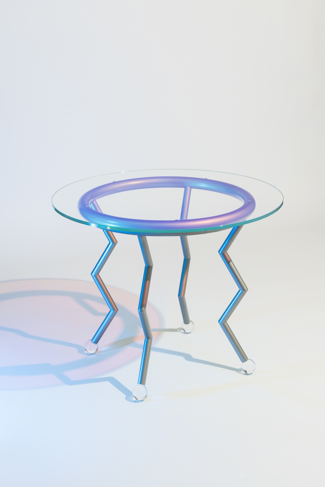 Medusa, Masanori Umeda, 2020 (based on a 1982 design), limited edition of 24 items + 1 artist's proof, “Night Tales” Collection, Post Design. Table with pale blue metal base, iridescent, dichroic glass top and round plexiglass feet. Dimensions: diameter 90, H 71.5 cm. Photograph © Delfino Sisto Legnani. Courtesy of Memphis srl. 