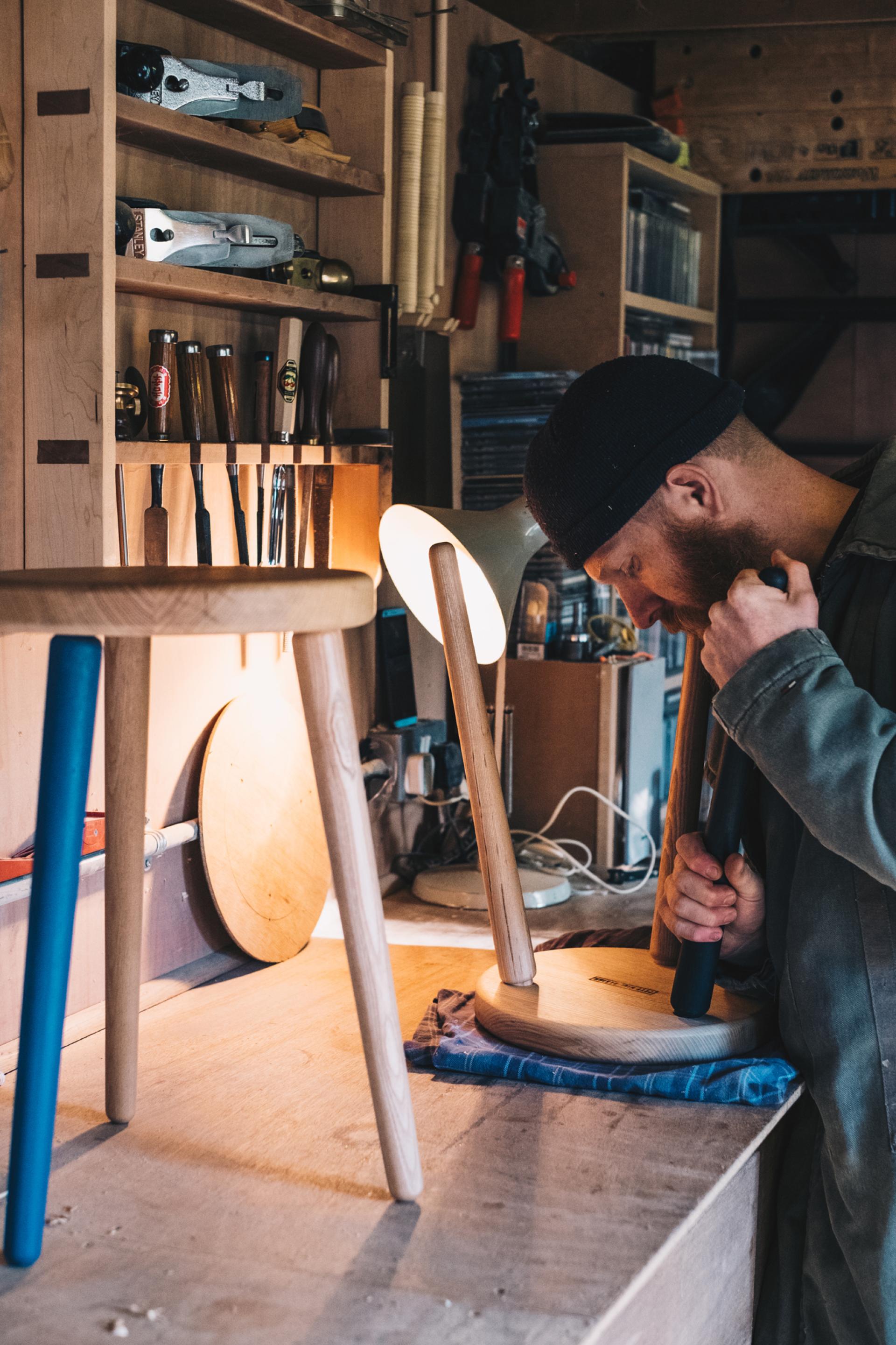 Craftsman focused on creating wooden furniture in a well-equipped workshop, showcasing craftsmanship and design skills.