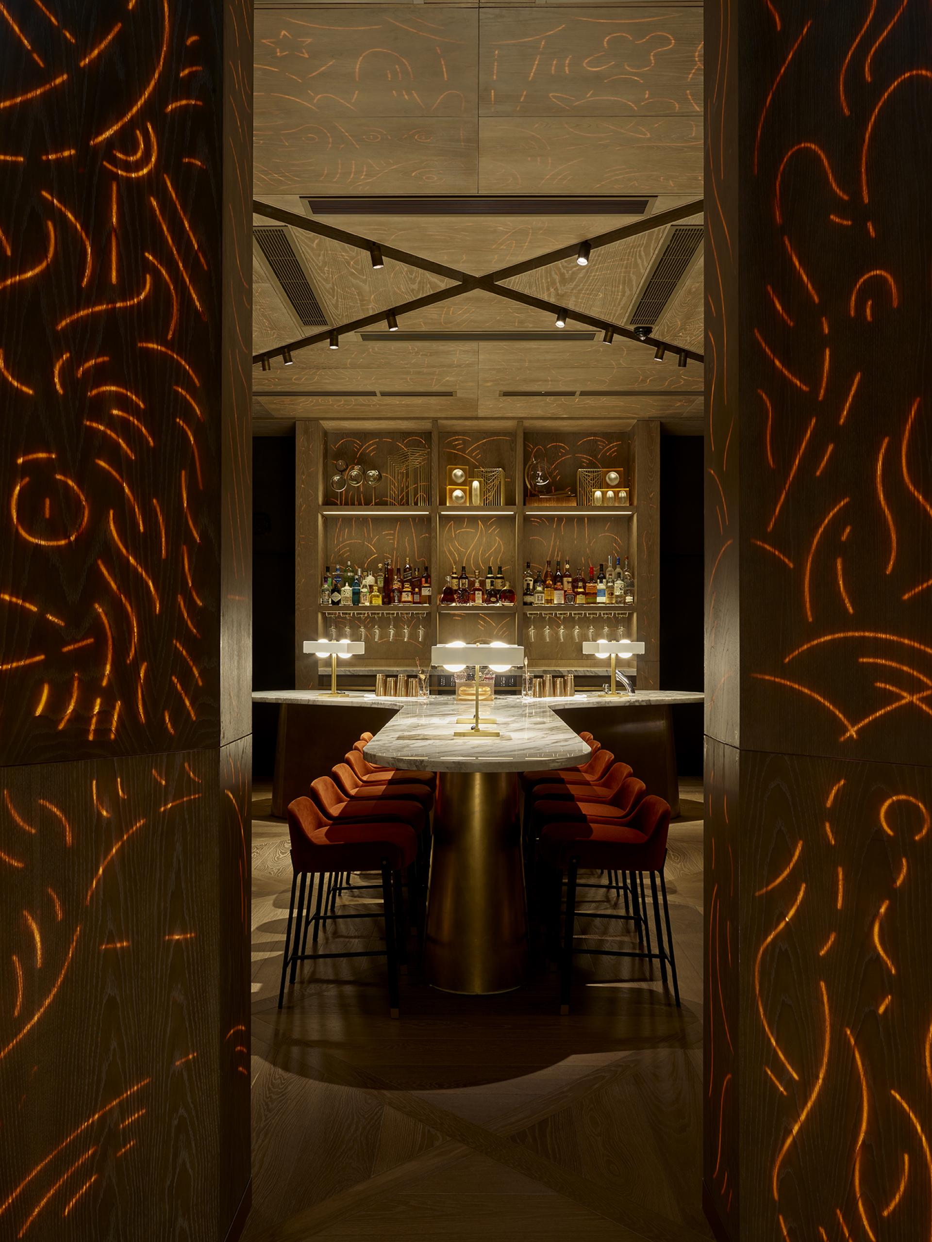 Elegant bar interior at Leicester Square hotel featuring illuminated wood patterns and stylish seating by Yabu Pushelberg.