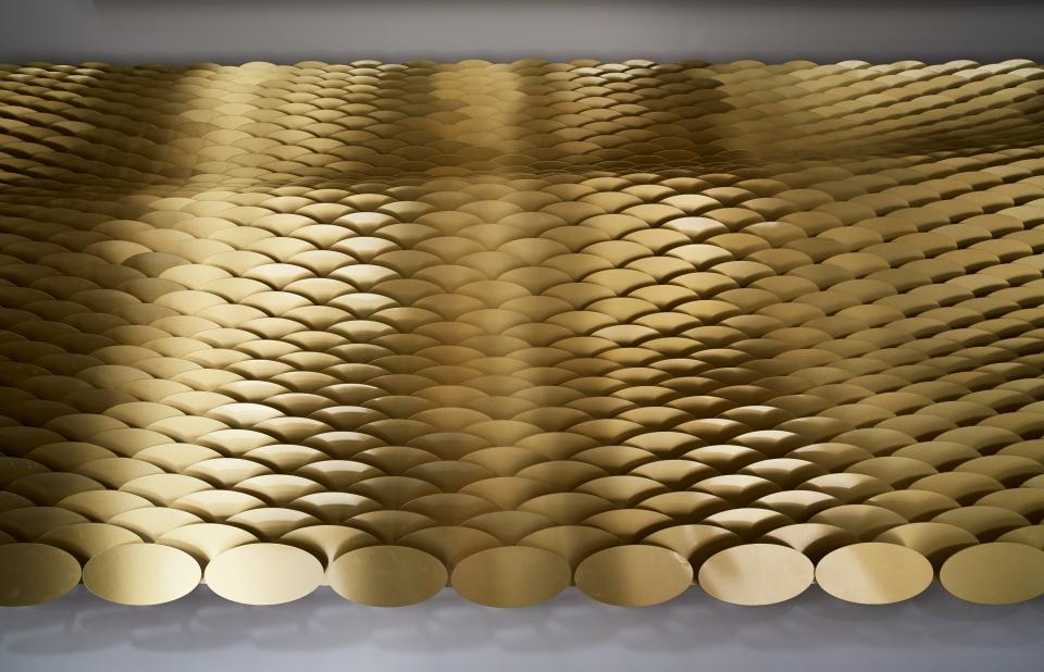 Intricate arrangement of brass louvres in a wave pattern, showcasing Giles Miller's architectural artwork, The Veil.