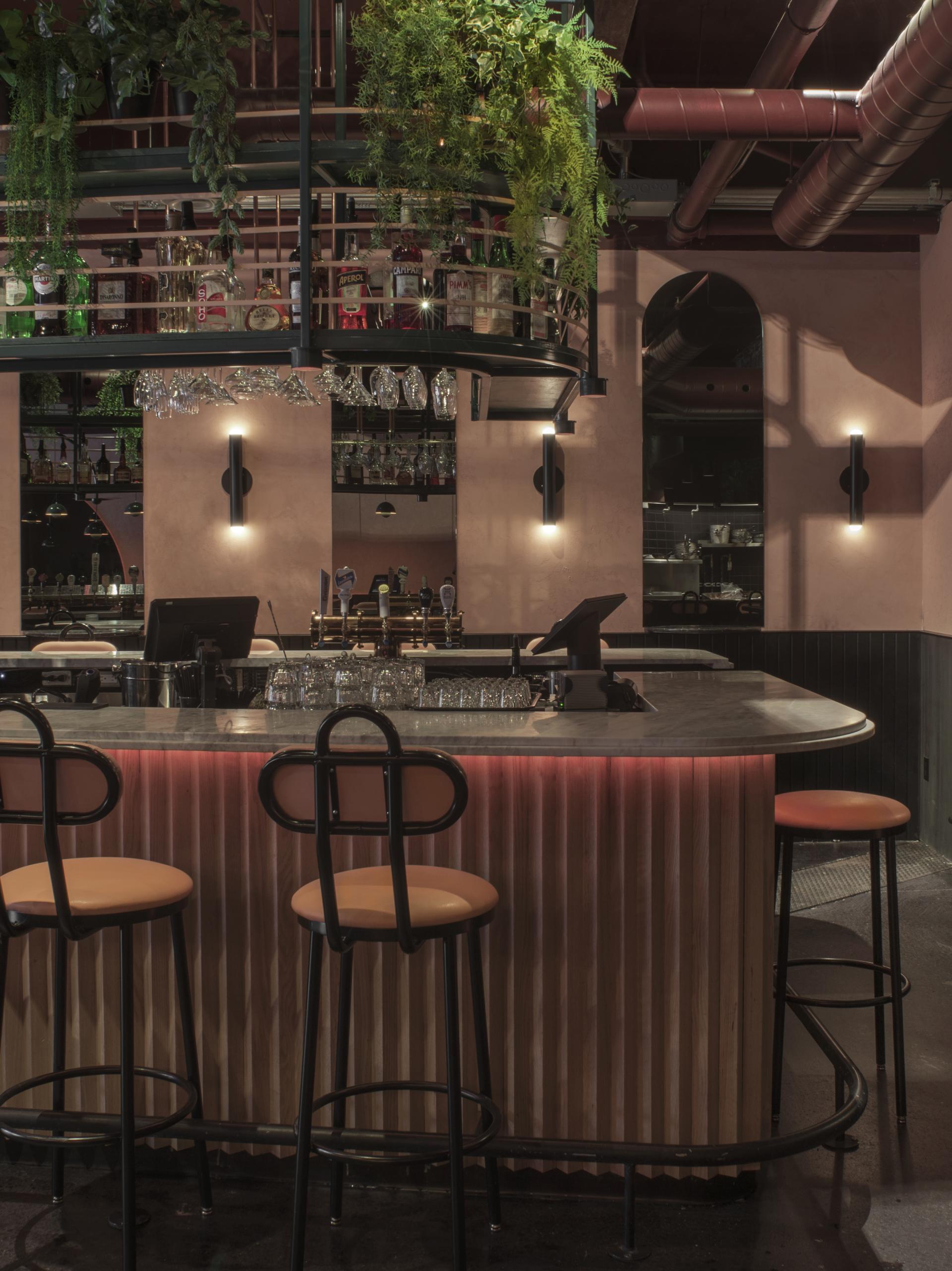 Tropical-themed bar with green plants, colorful liquor bottles, and stylish seating in a modern Montreal restaurant.