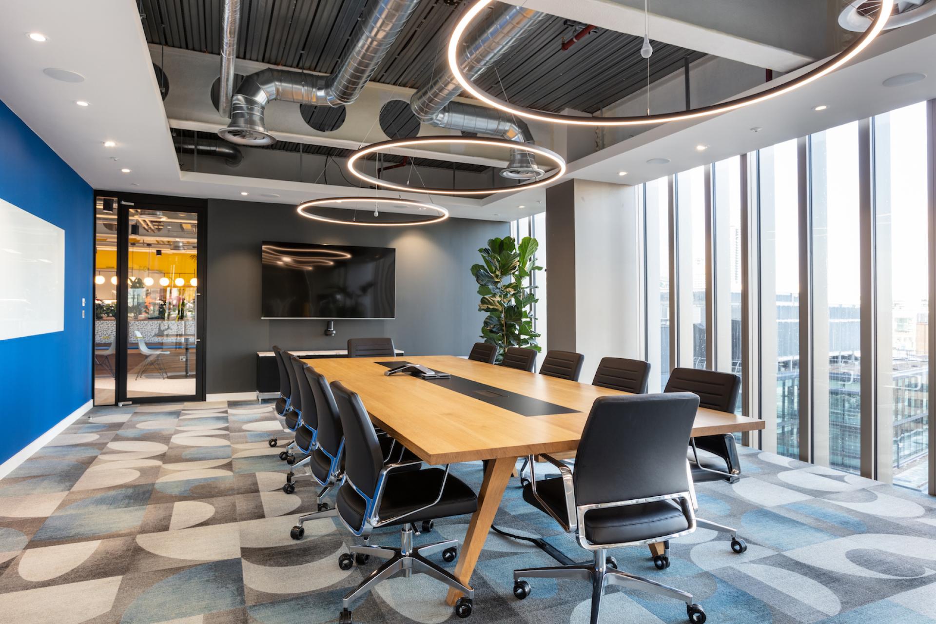 Modern conference room featuring a sleek wooden table, ergonomic chairs, and large windows enhancing natural light.
