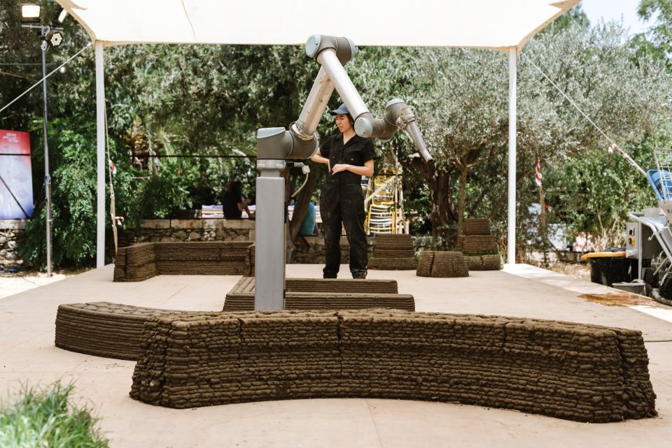3D printing robot constructing earthen structures at Jerusalem Design Week, demonstrating innovative building techniques.
