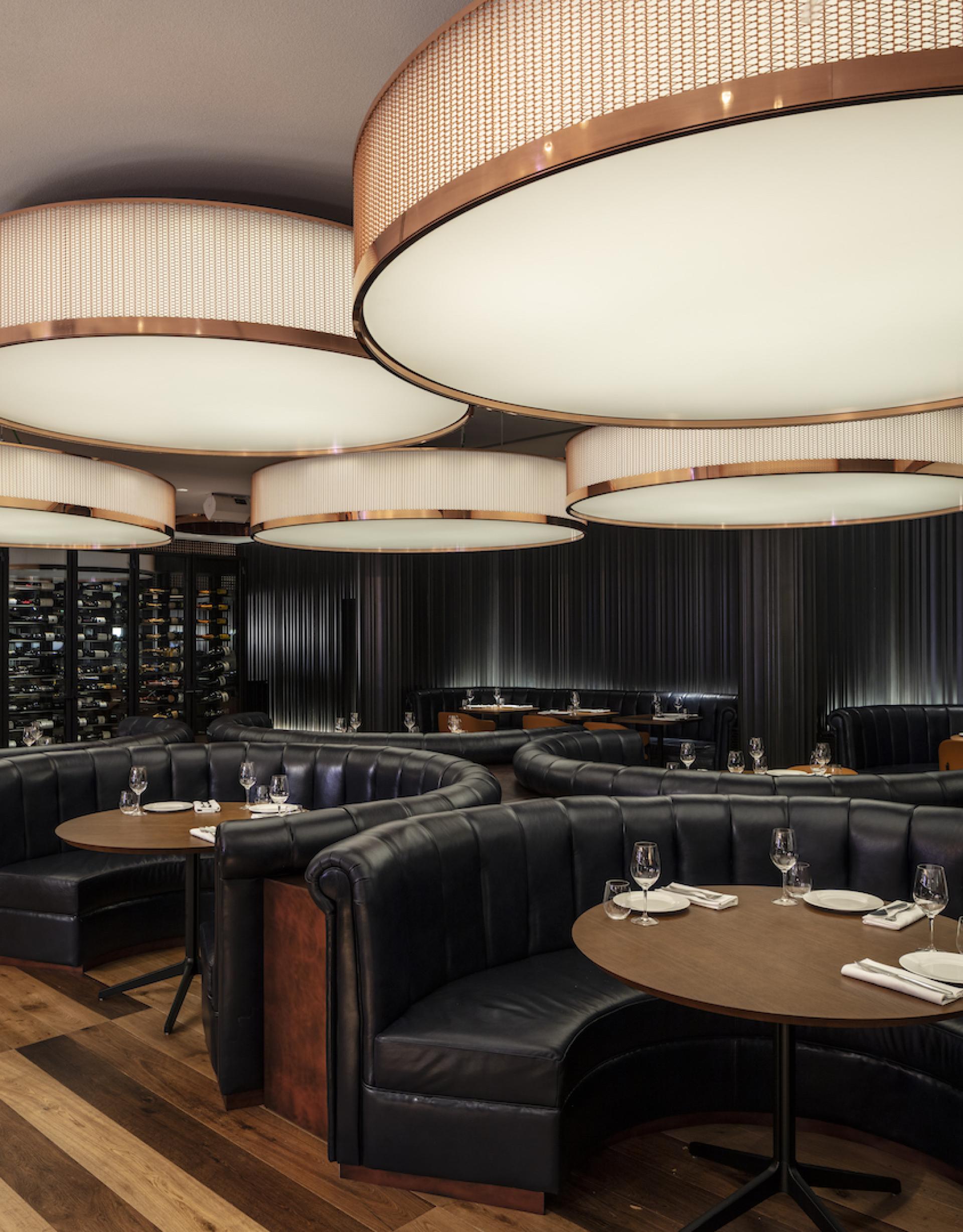 Luxurious dining area in Sir Victor hotel, featuring stylish booths, elegant lighting, and a sophisticated wine display.