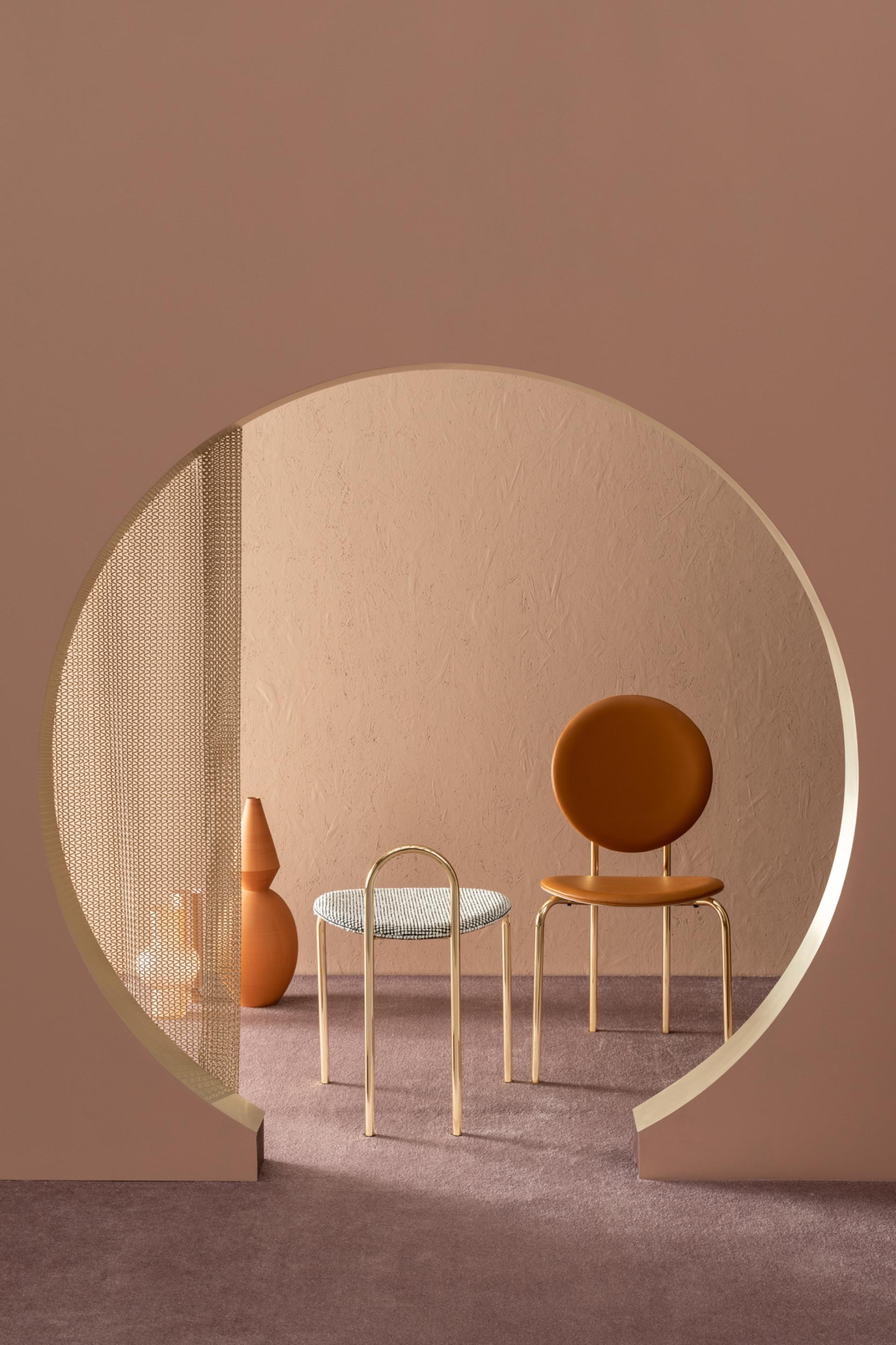 Contemporary furniture design featuring a stylish chair and stool in warm tones against a textured backdrop.