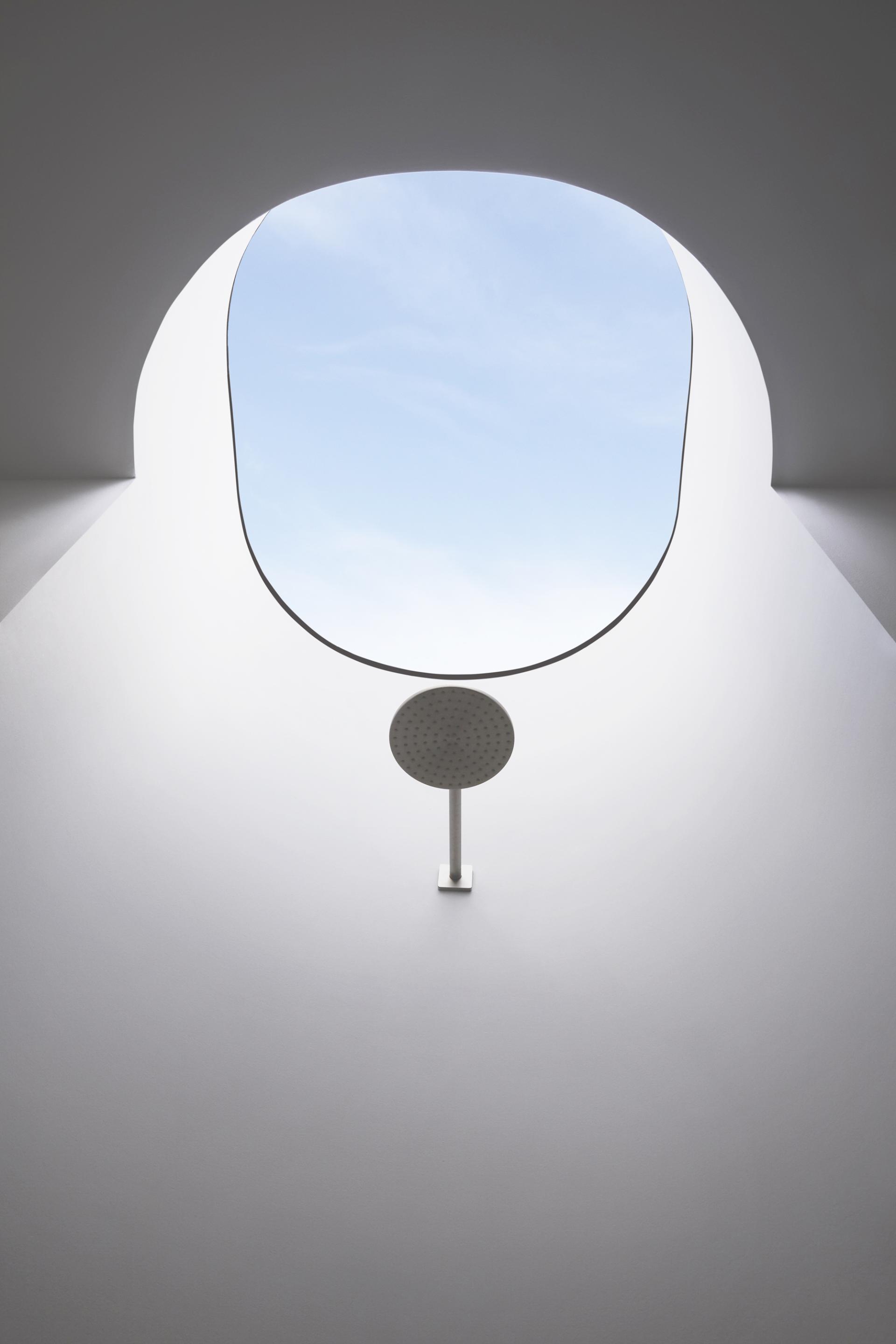 Circular skylight framing a clear blue sky above a modern minimalist space, showcasing THISS architecture and design principles.