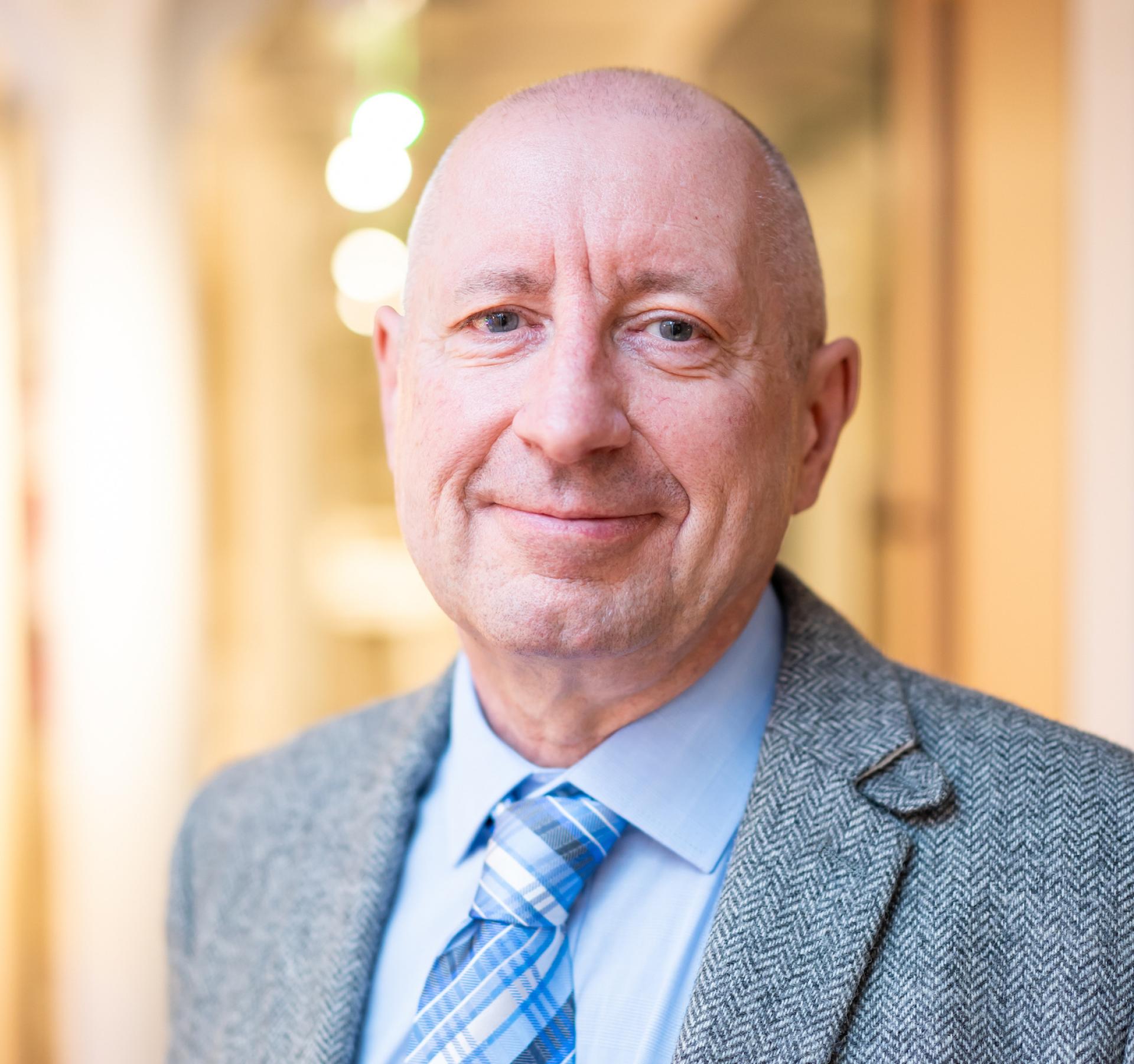 Confident educator smiling in a modern setting, reflecting changes and future trends in education after the pandemic.