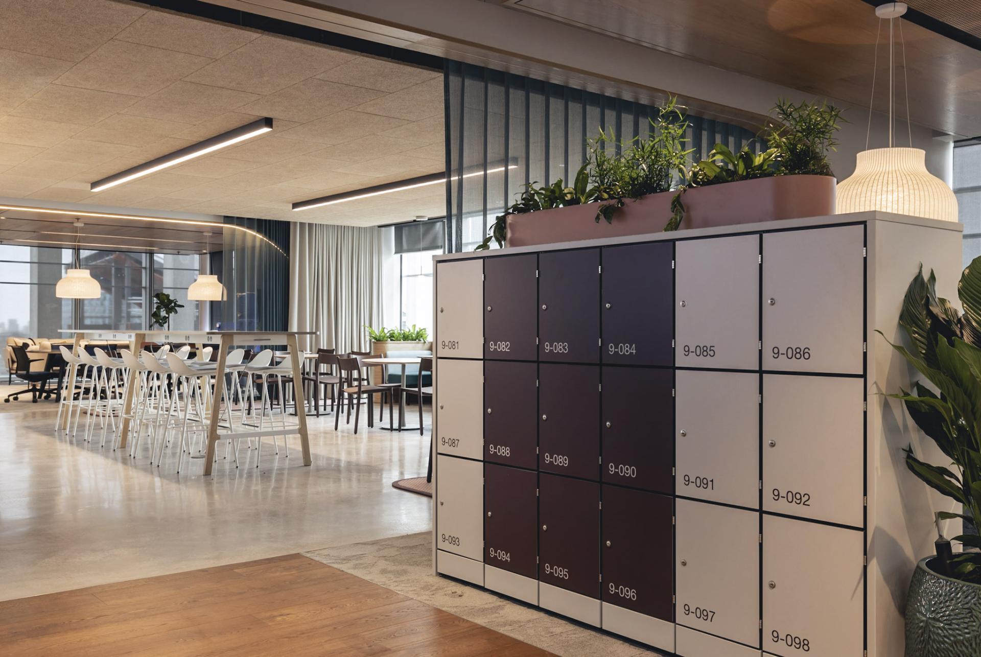 Modern office space featuring lockers, communal seating, and greenery, highlighting creativity and collaboration at Ekho Studio.