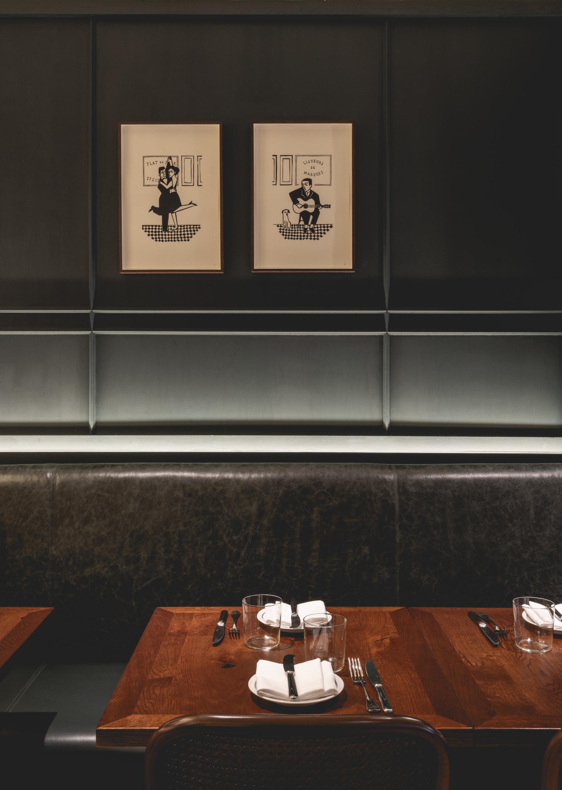 Modern restaurant interior featuring Parisian-inspired artwork, wooden tables, and stylish table settings in a cozy ambiance.